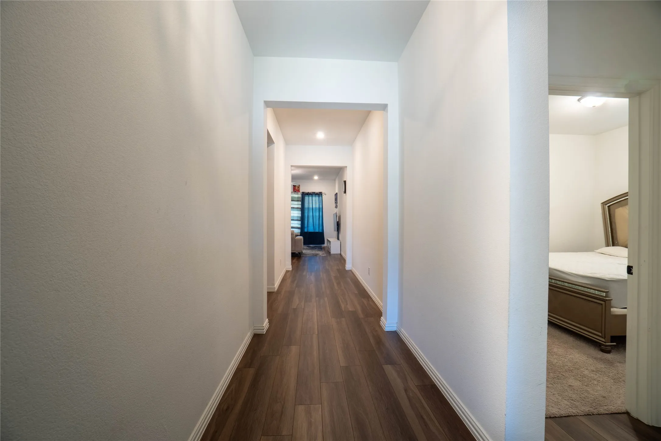 Hallway featuring wood-finish flooring, recessed lighting, white baseboards, and neutral wall finishes