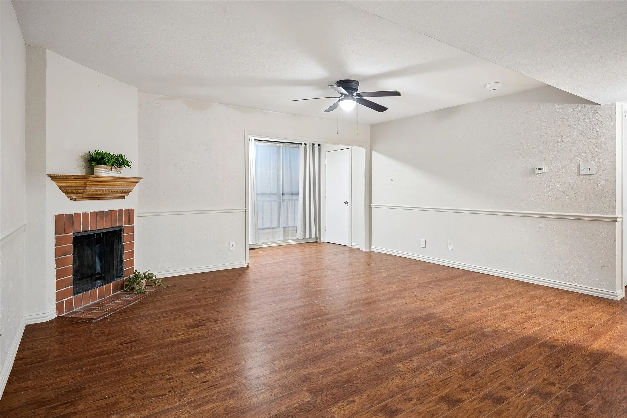 Pretty laminate wood flooring, electric fireplace, chair rail and modern ceiling fan accent the living space.