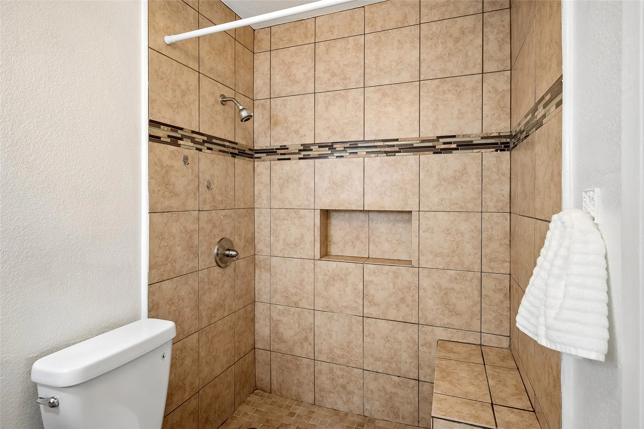 Primary shower with seat and cut-out for shampoo.
