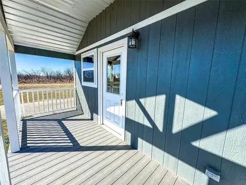 Covered front porch featuring durable composite decking, white railing, and a corrugated metal ceiling