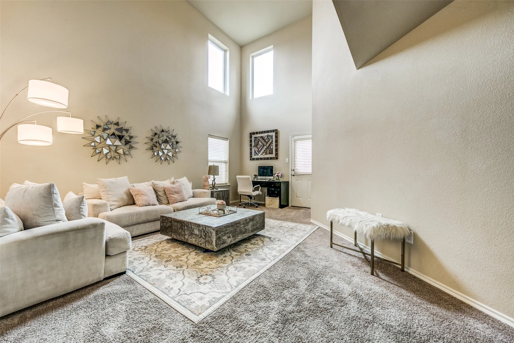 Living area featuring a soaring ceiling, upper windows, and soft carpeting