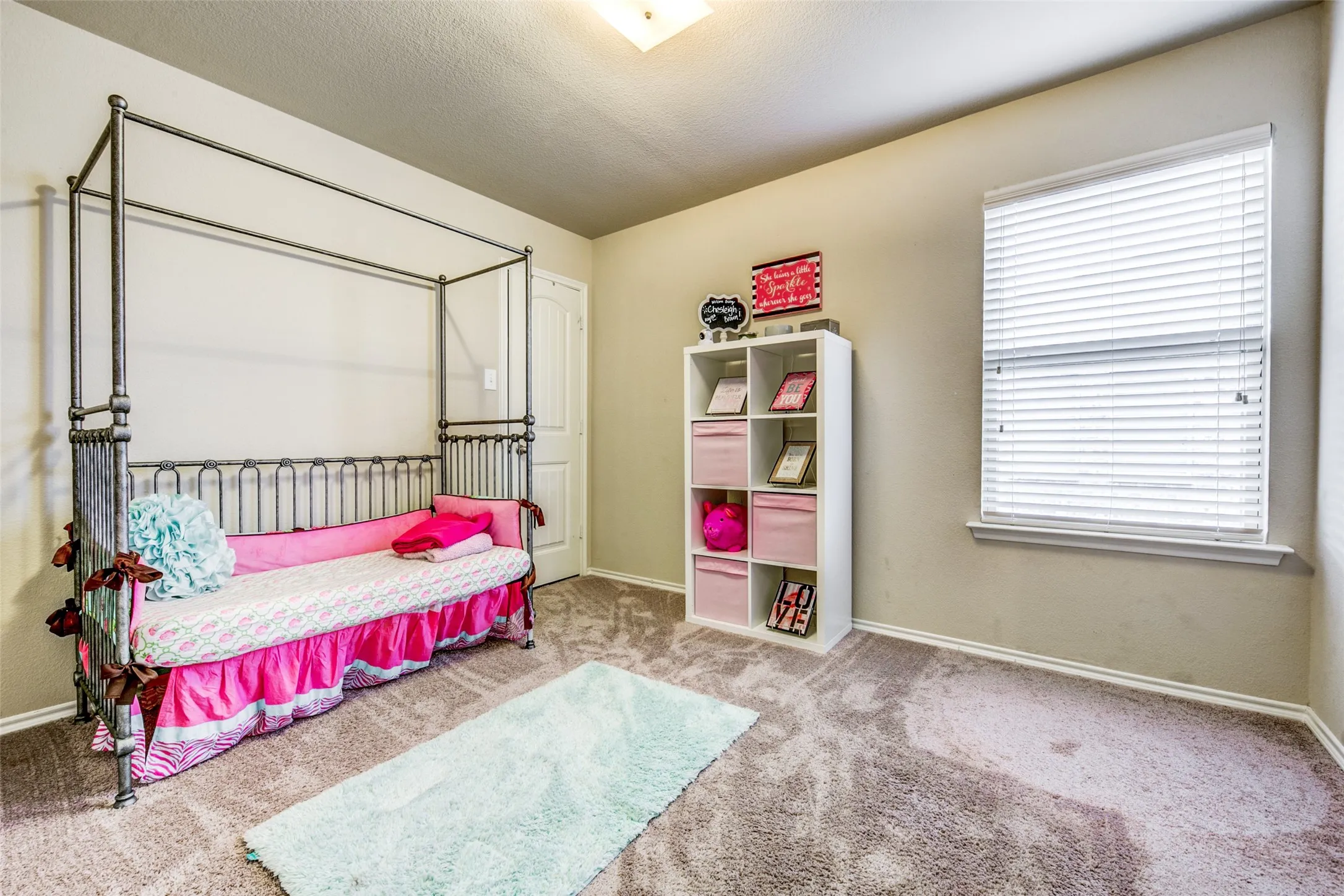 Spacious room featuring neutral wall tones, plush carpet, and a single window with blinds