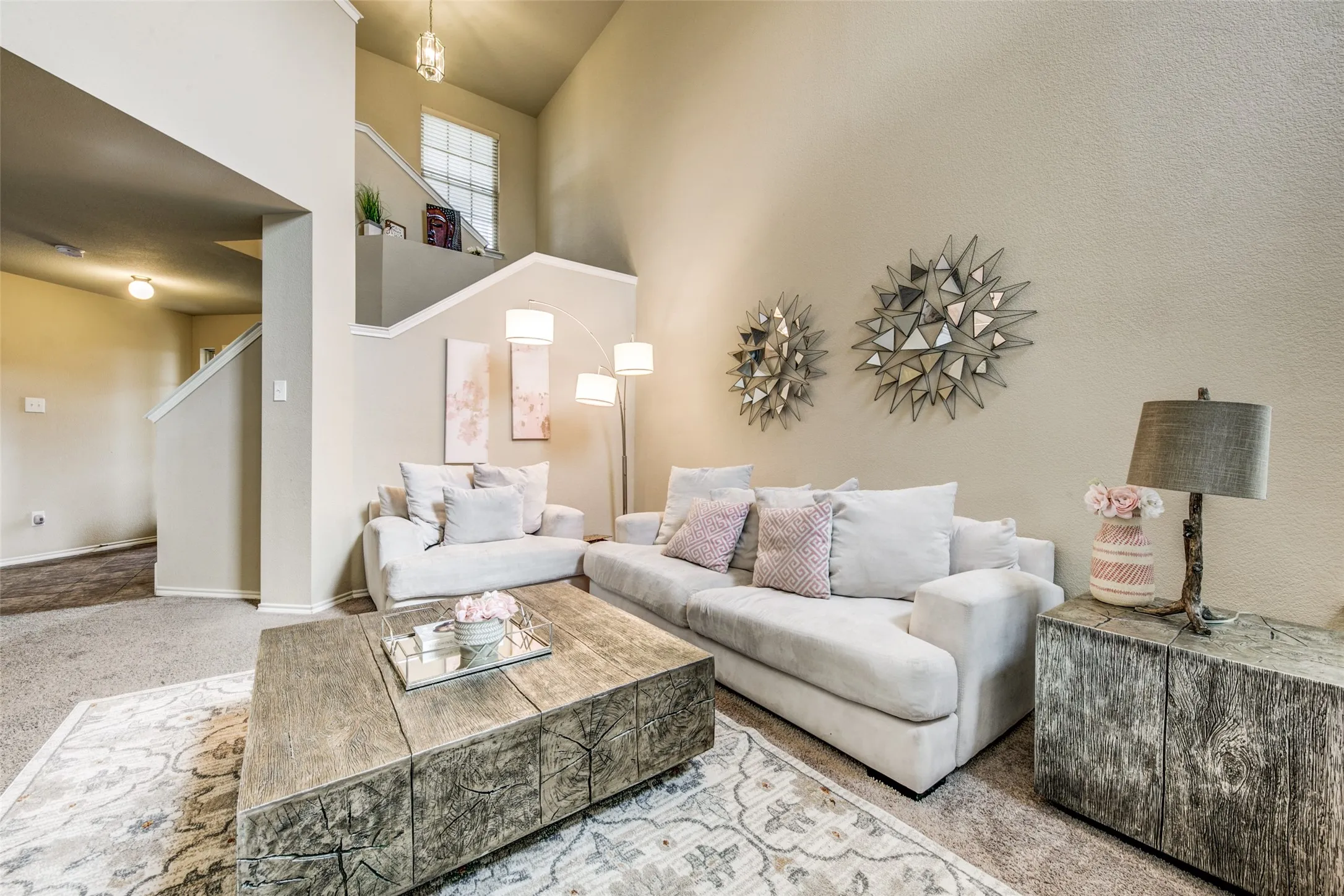 Spacious living area featuring a vaulted ceiling, neutral paint finishes, a prominent staircase, and soft carpet​​‌​​​​‌​​‌‌​‌‌​​​‌‌​‌​‌​‌​​​‌​​ flooring