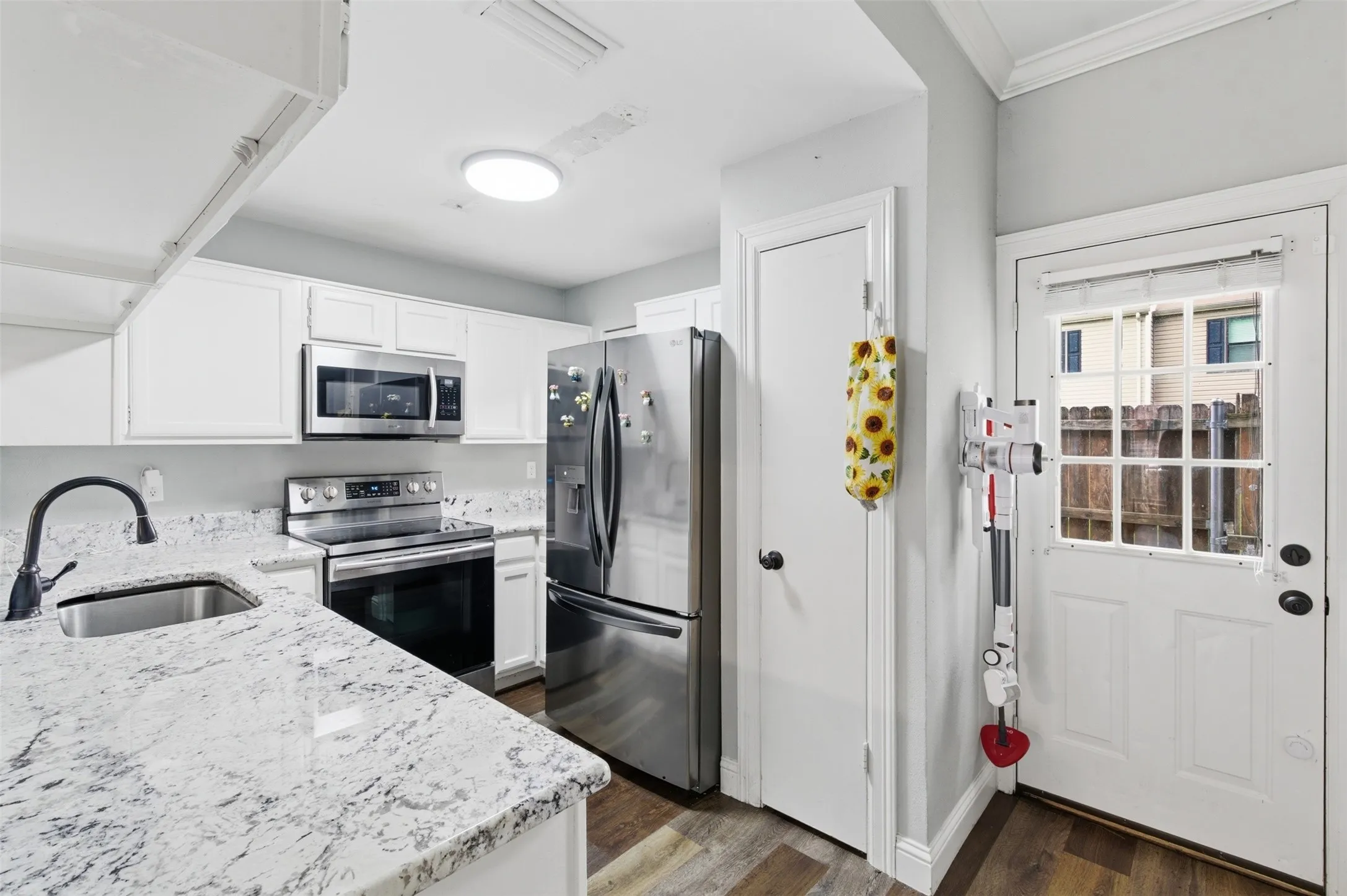Kitchen featuring white cabinetry, light-toned countertops, stainless steel appliances, and wood-finish flooring