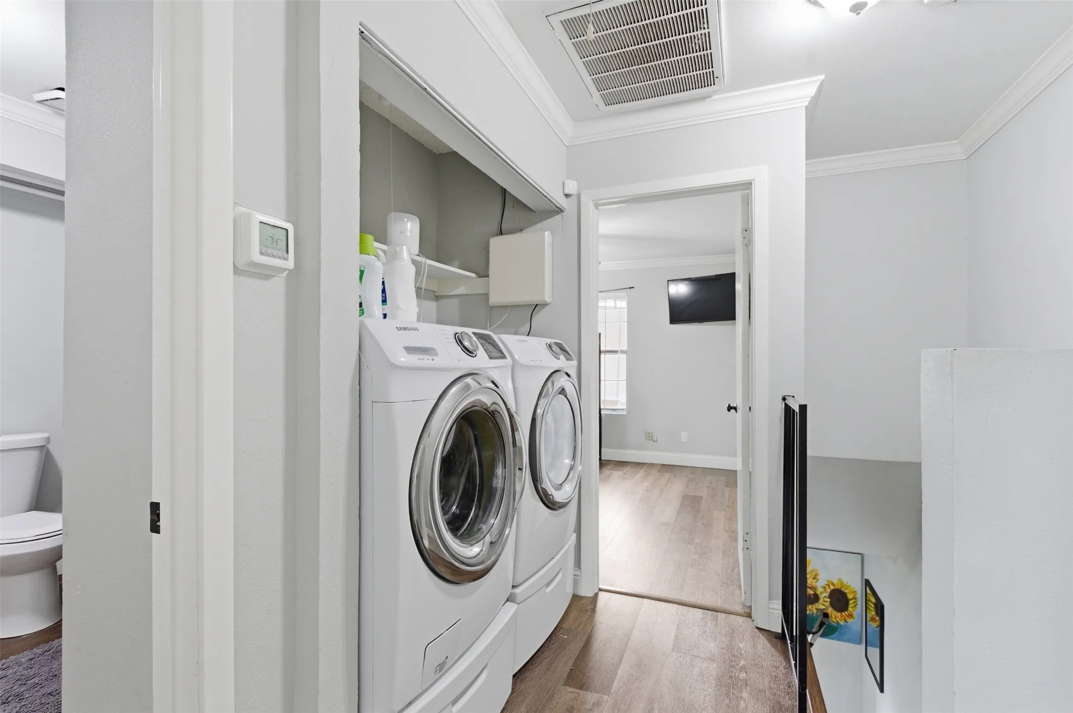 Dedicated laundry area featuring a white stacked washer and dryer unit, built-in shelving, and recessed lighting