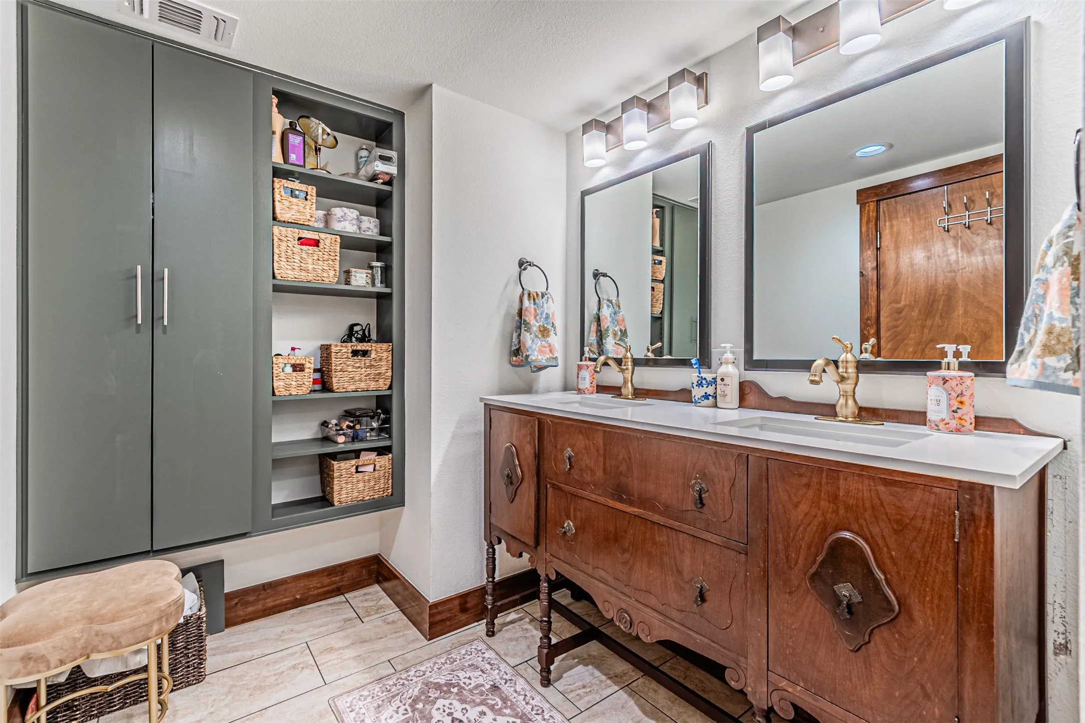 Double vanity with a white countertop and brass-finish faucets, complemented by dual framed mirrors and sconce lighting