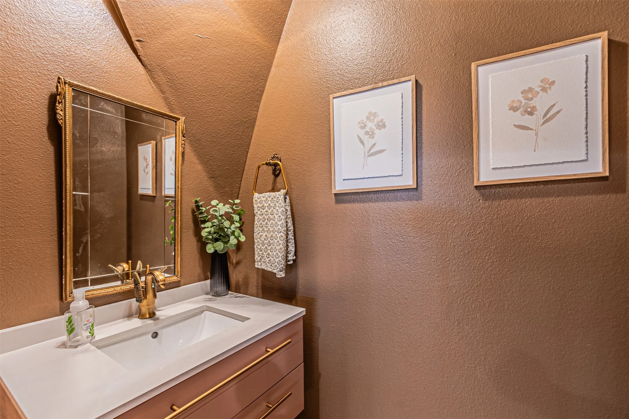 Bathroom vanity with integrated sink, gold-finish faucet, and coordinating gold-finish drawer pulls