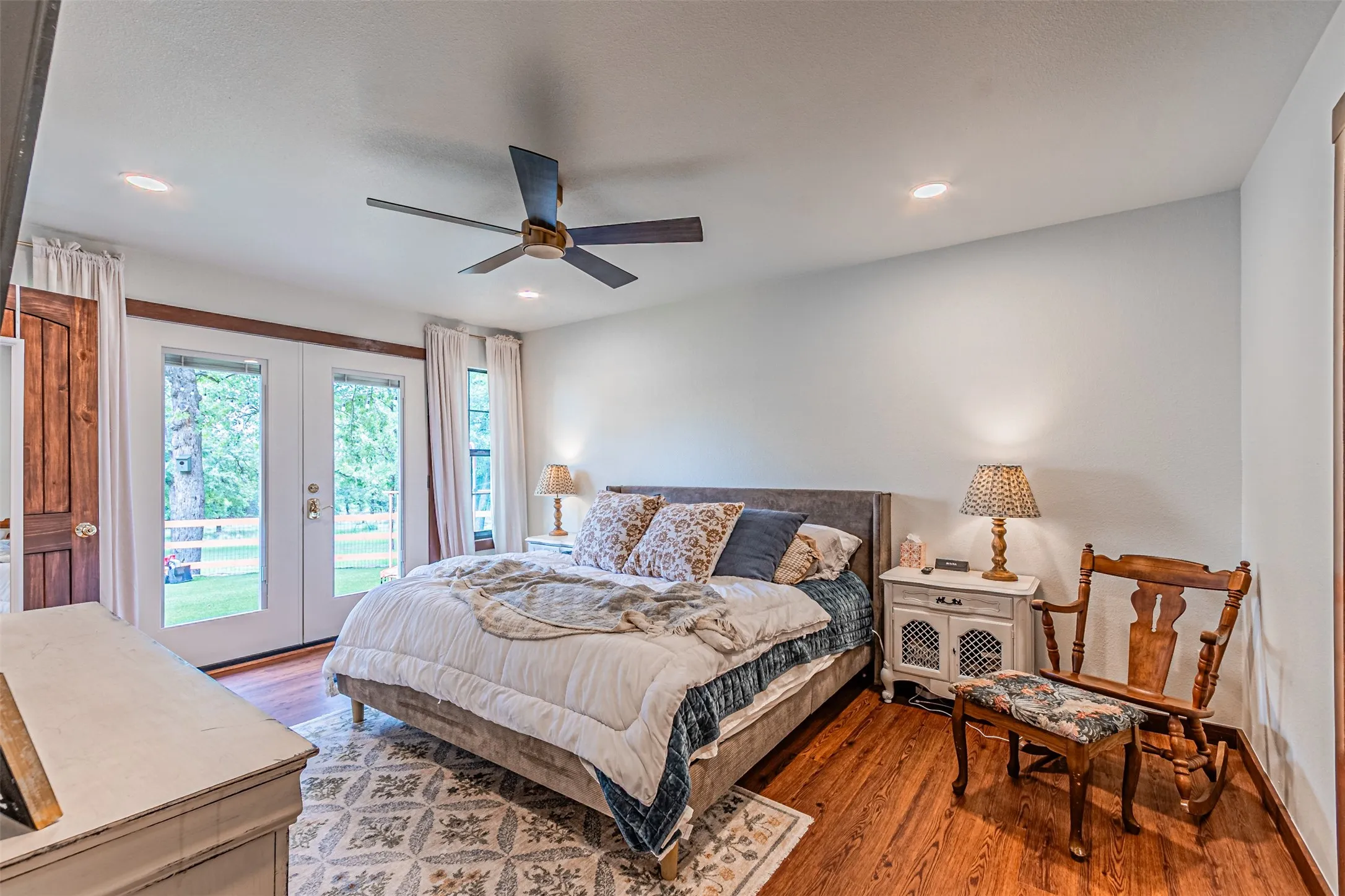 Bedroom featuring wood-finish flooring, white walls, and a ceiling fan with integrated lighting