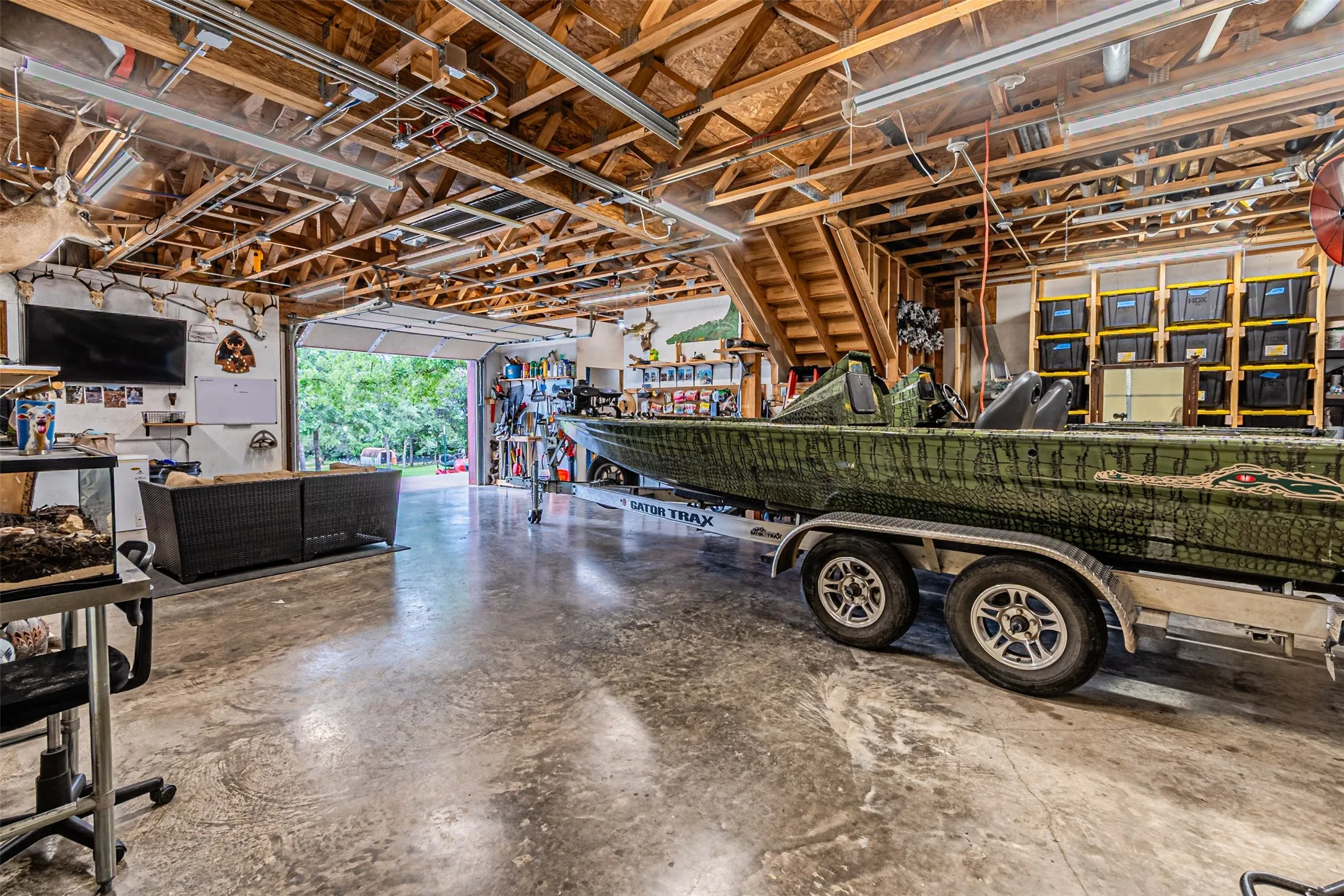 Spacious garage with exposed wood beam ceiling, concrete flooring, and a large overhead door