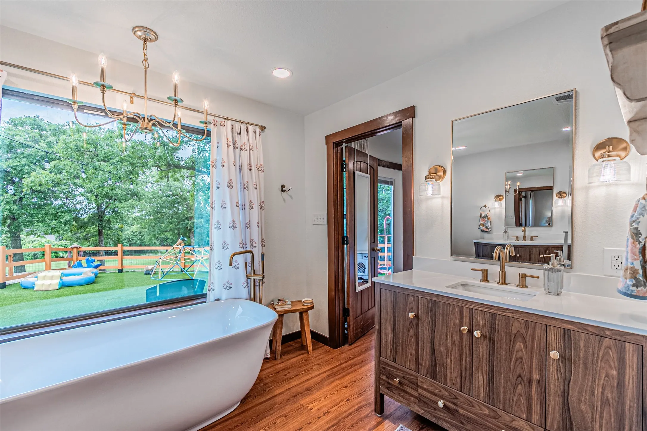 Freestanding soaking tub positioned before a large picture window, offering expansive views of the exterior