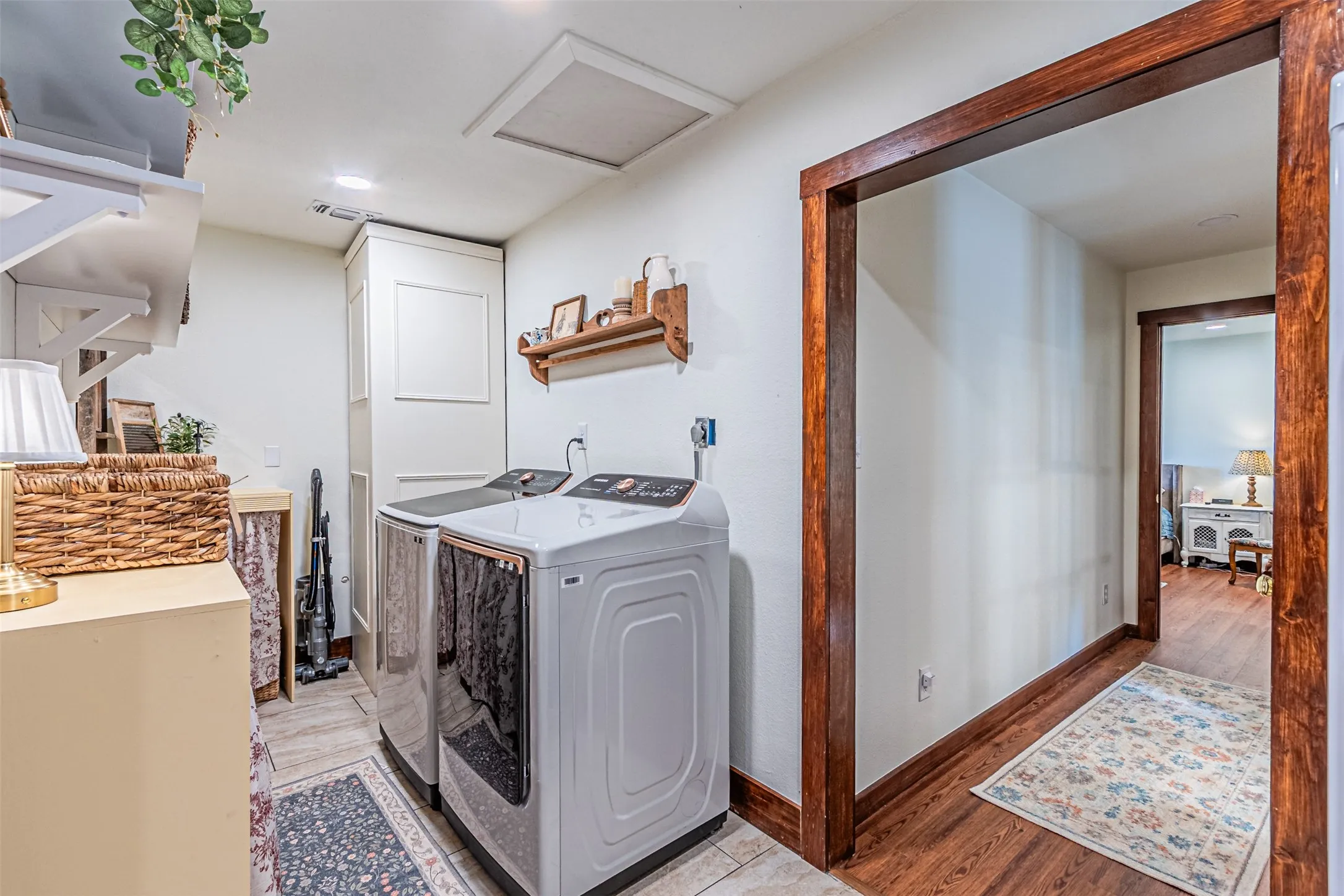 Laundry area featuring tile flooring, white shelving, and a built-in cabinet