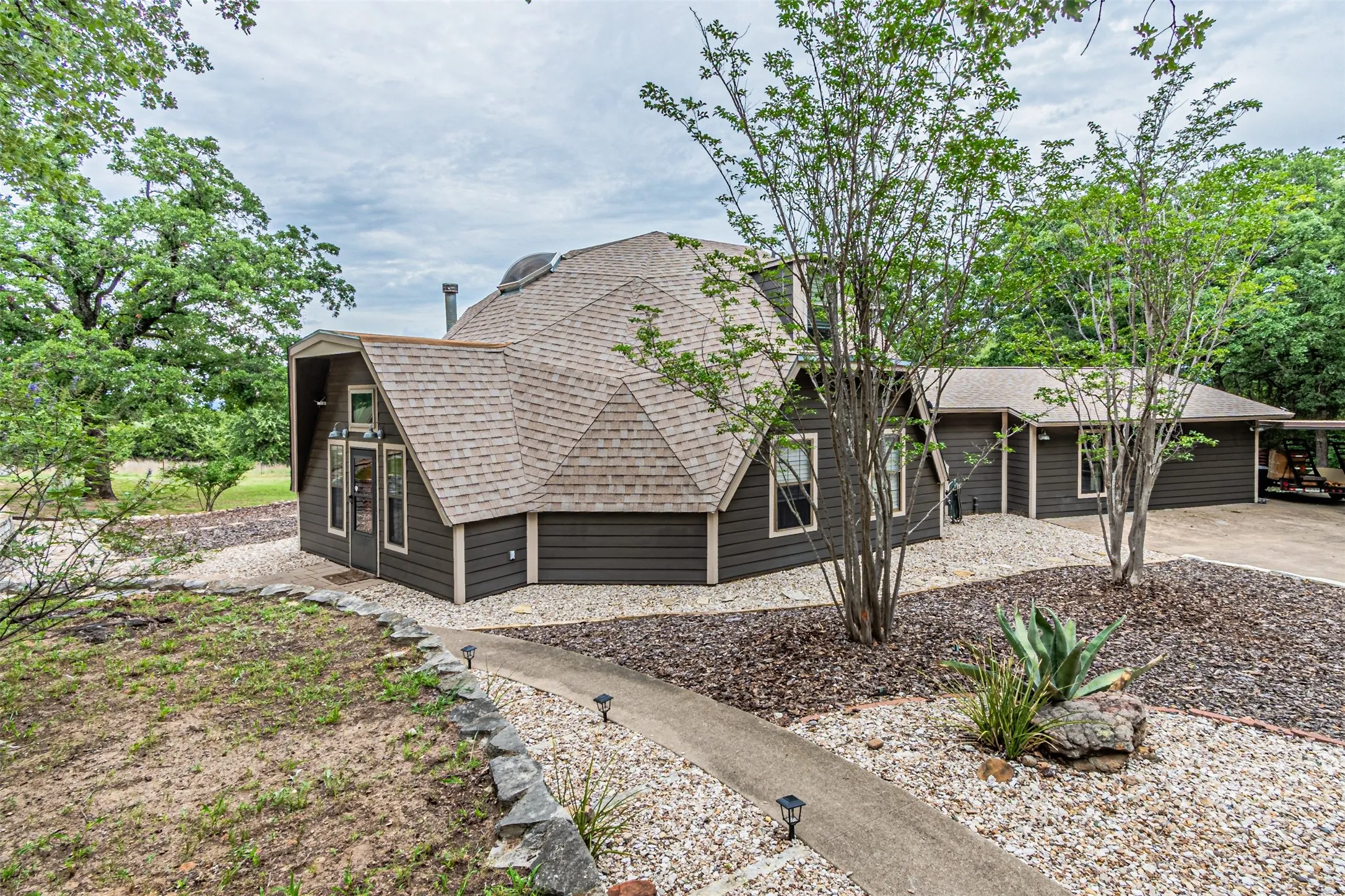 Geodesic dome structure featuring dark gray siding and a light gray shingle roof