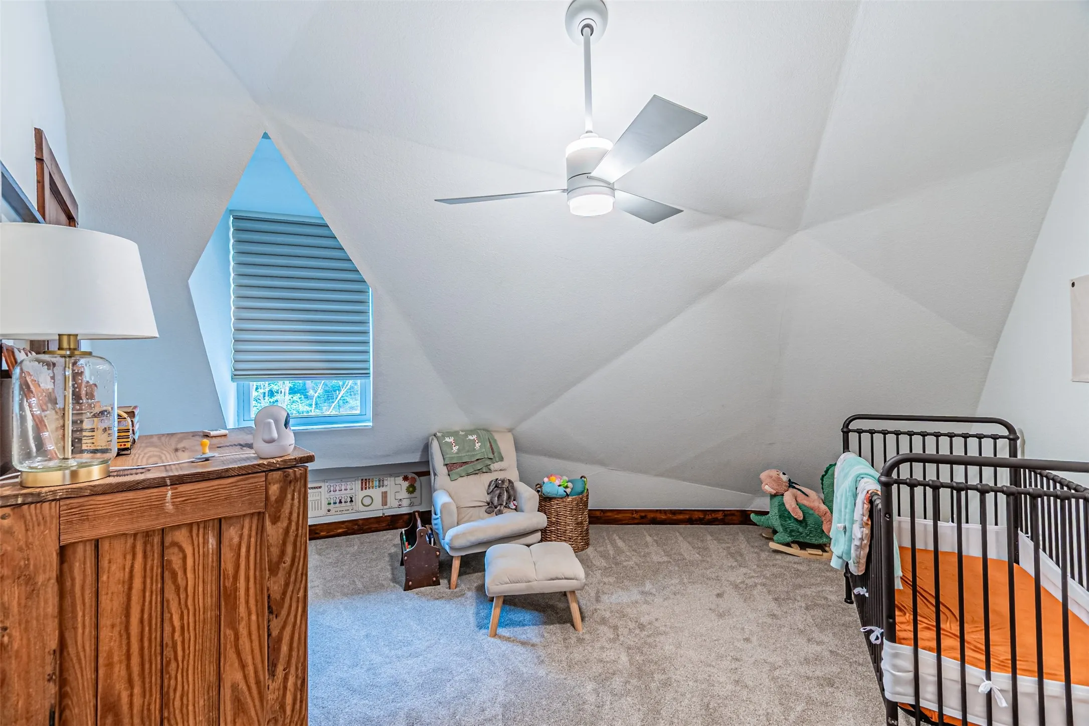Attic room featuring sloped ceilings, a window with horizontal blinds, wood-finish baseboards, and carpeted flooring