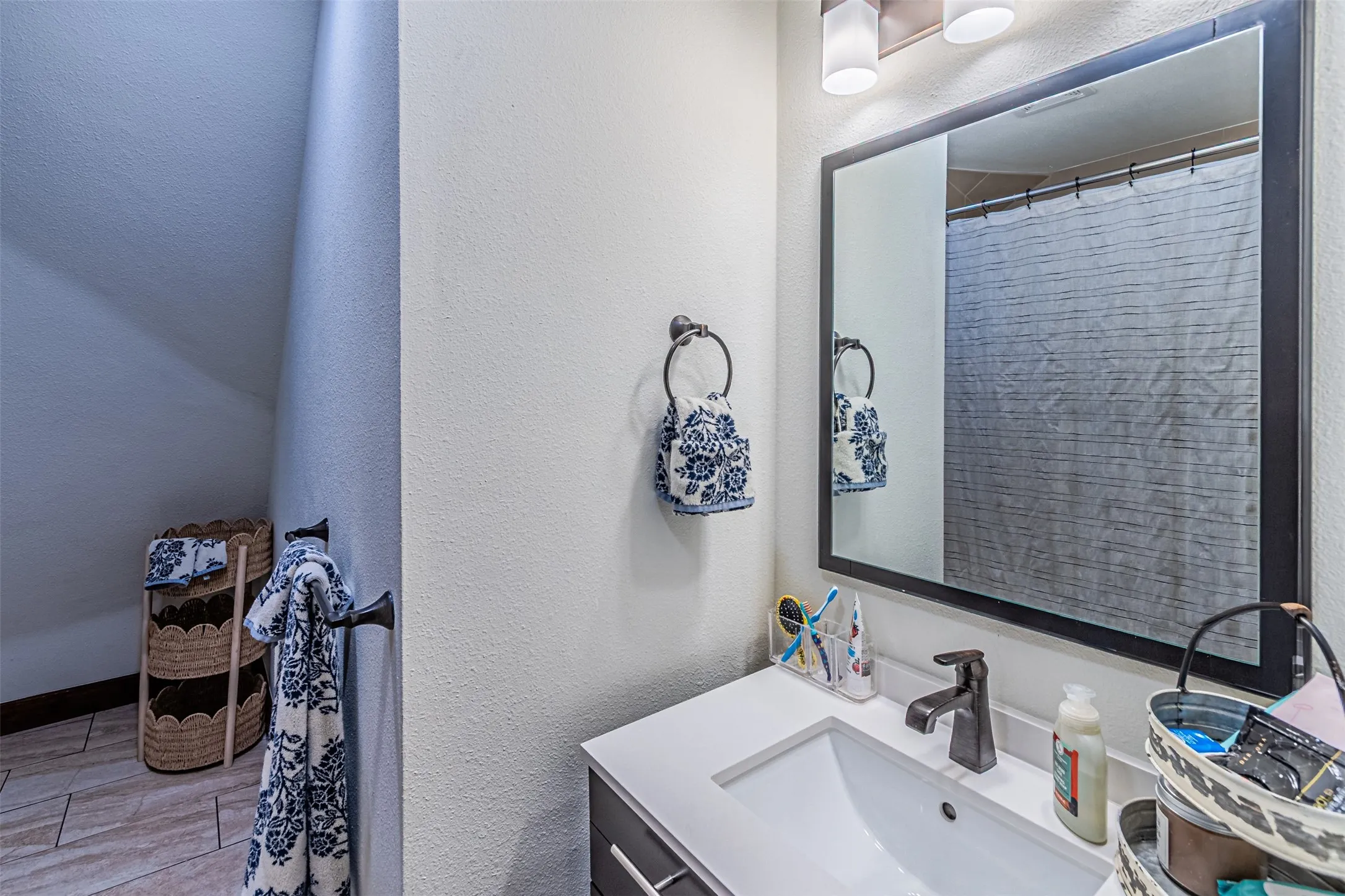 Bathroom vanity featuring a rectangular undermount sink, a dark bronze single-handle faucet, and a large framed mirror