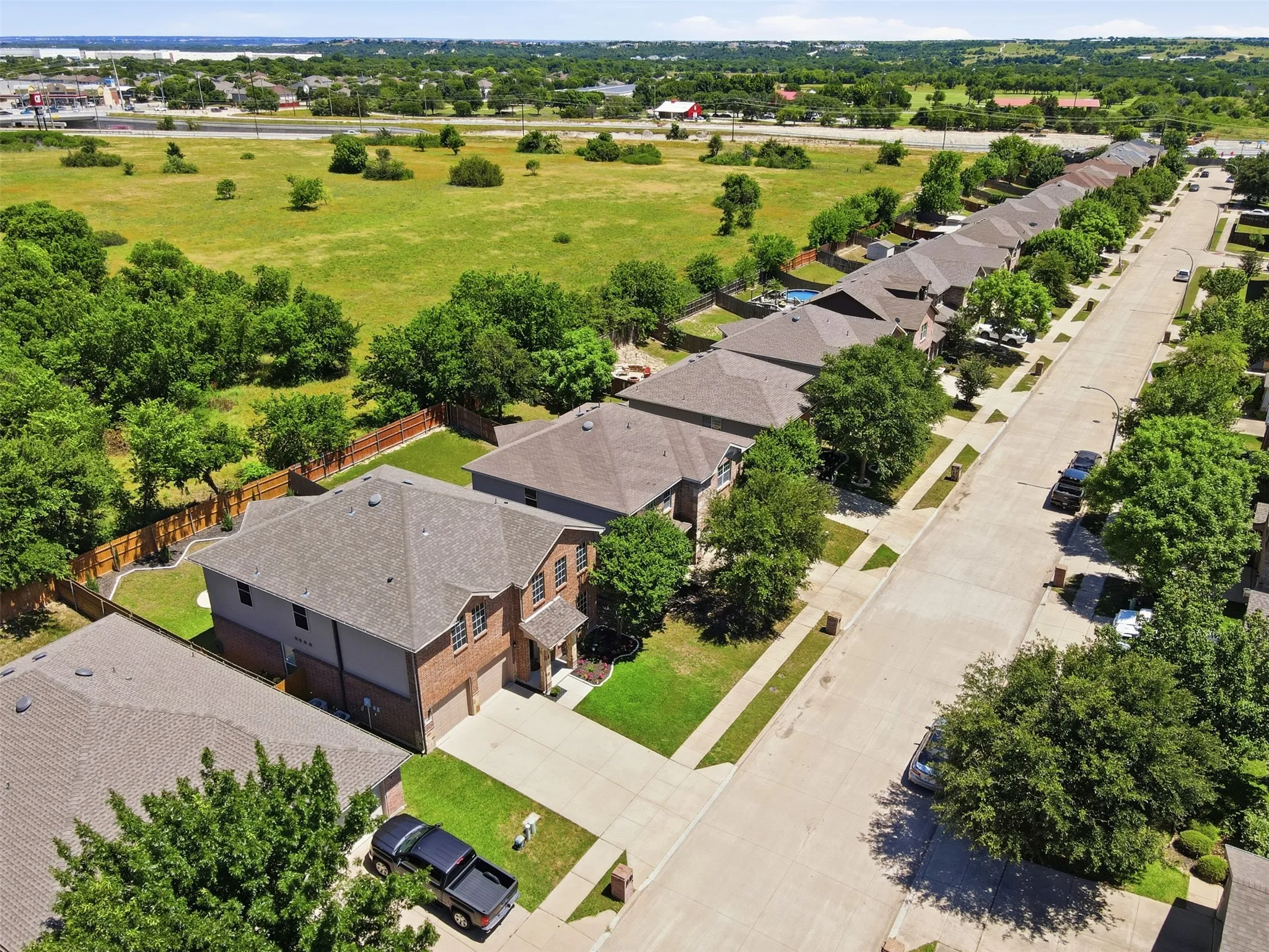 Aerial perspective showcasing a residential street lined with homes featuring brick and siding exteriors, private driveways, and mature trees