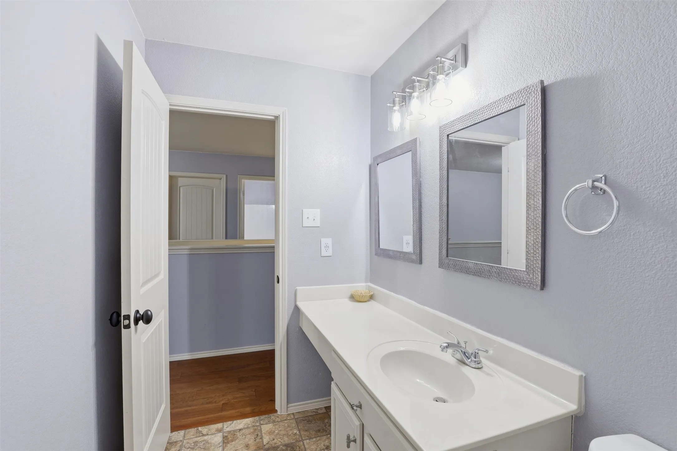 Bathroom vanity featuring a single basin, laminate countertop, and dual framed mirrors