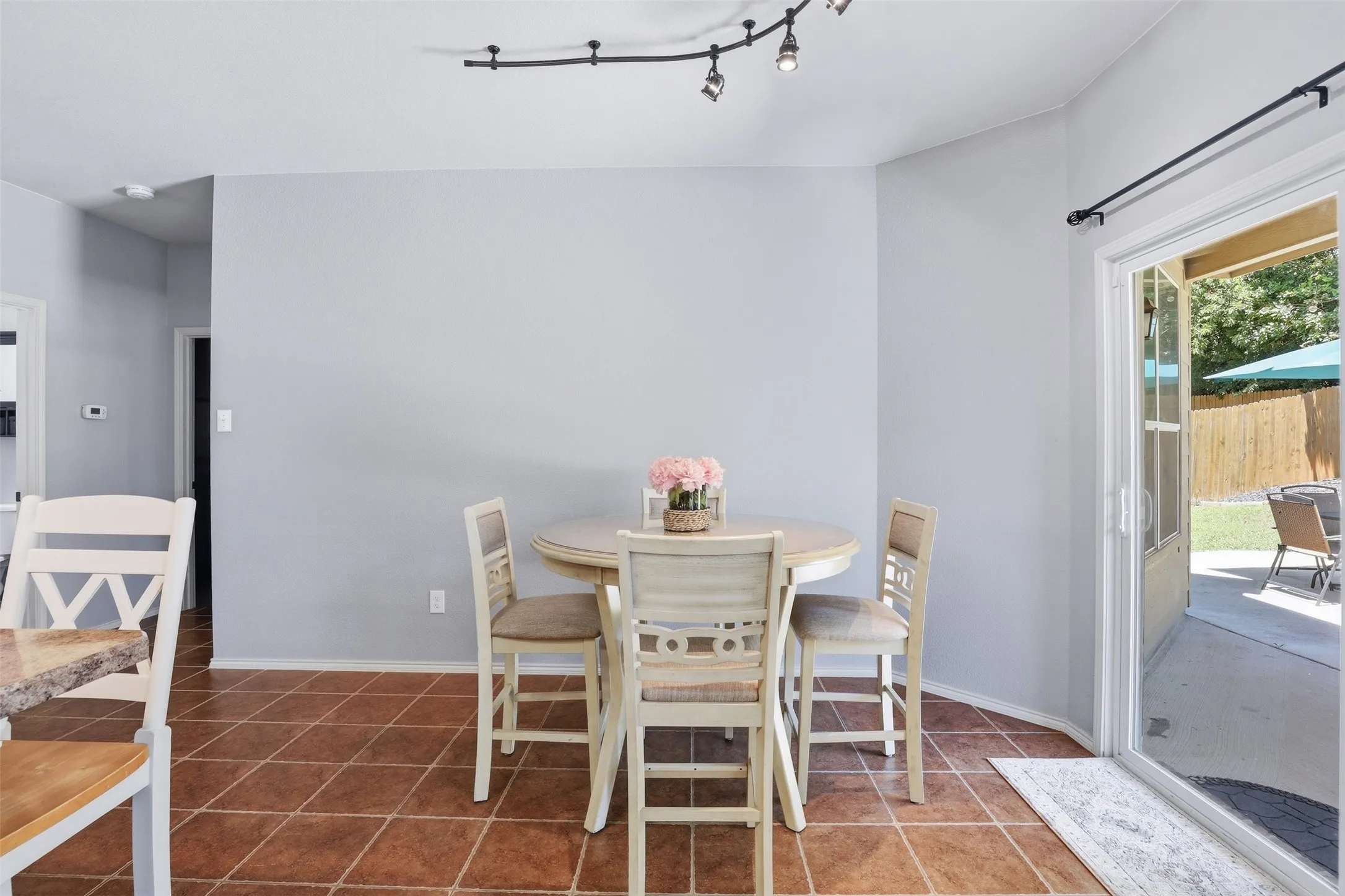 Dining area featuring track lighting, terracotta-style floor tiling, a sliding glass door, and direct patio access