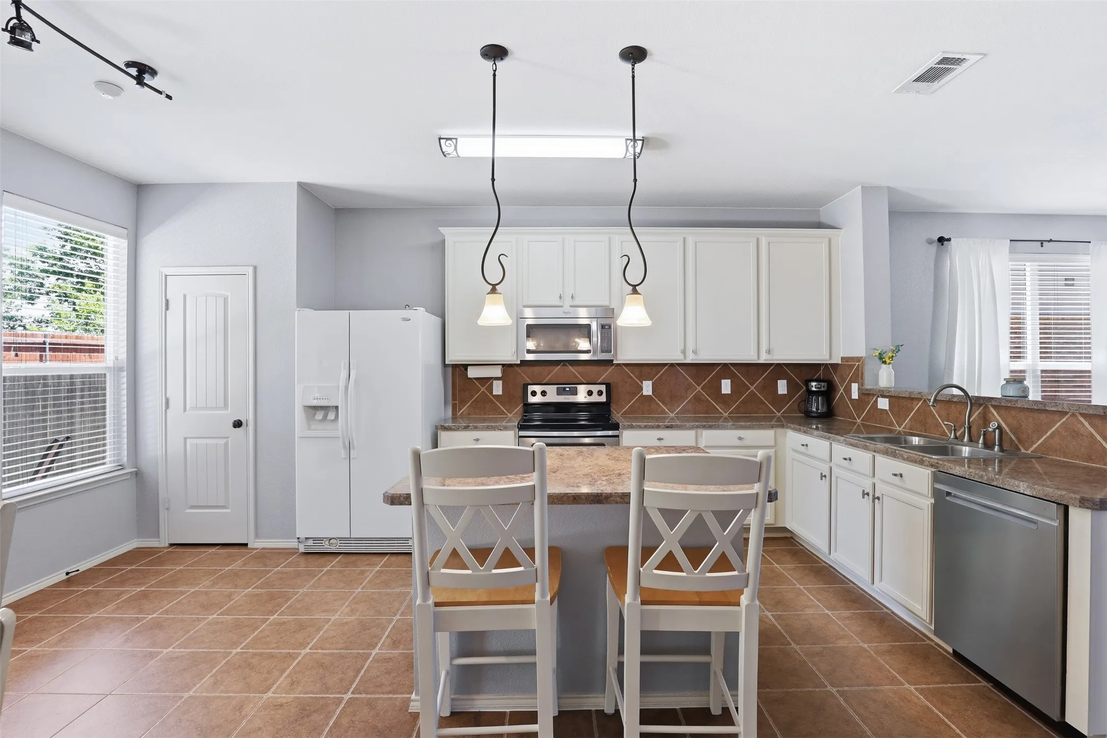 Spacious kitchen featuring white cabinetry, stainless steel appliances, and a tiled backsplash