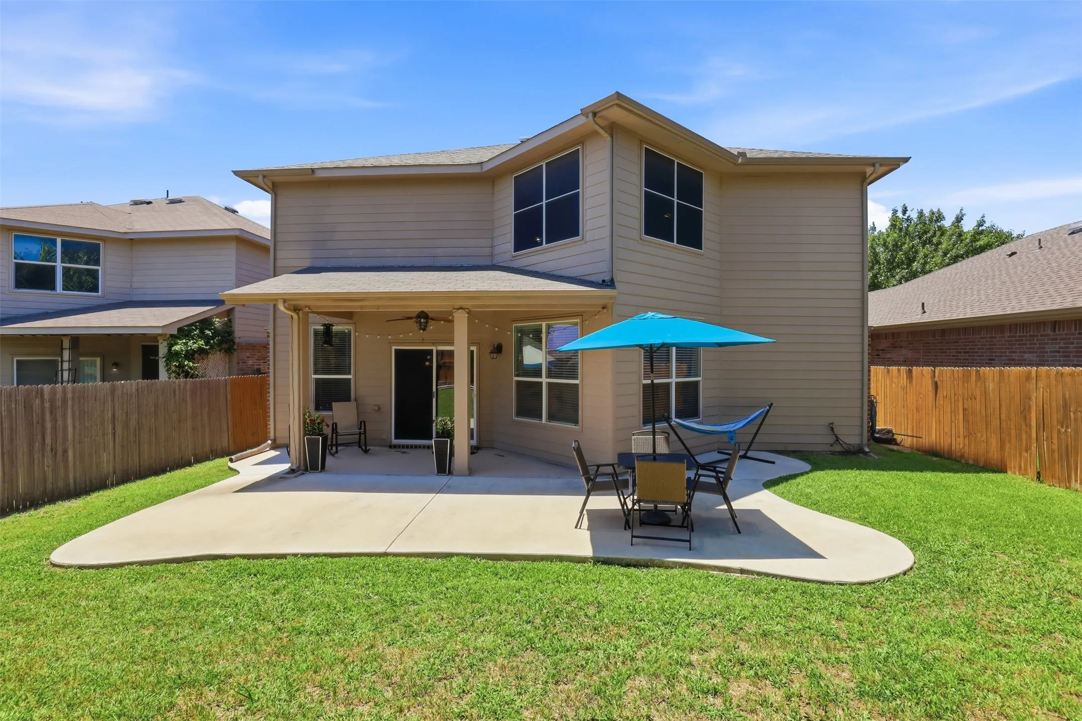 Expansive backyard featuring a manicured lawn, a large concrete patio, and a covered porch area