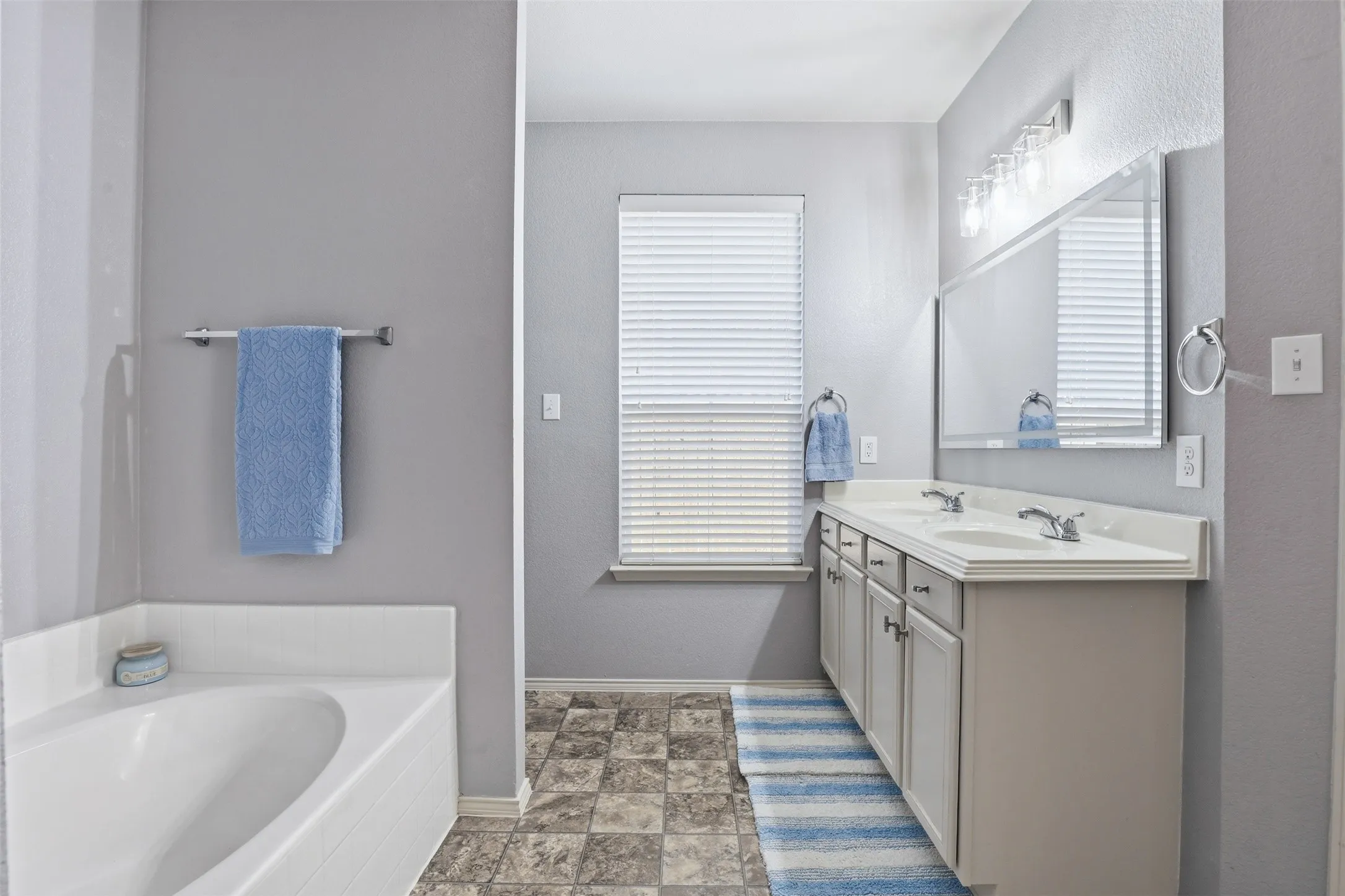 Primary bathroom featuring a built-in soaking tub, dual vanity with undermount sinks, and a framed mirror with overhead lighting