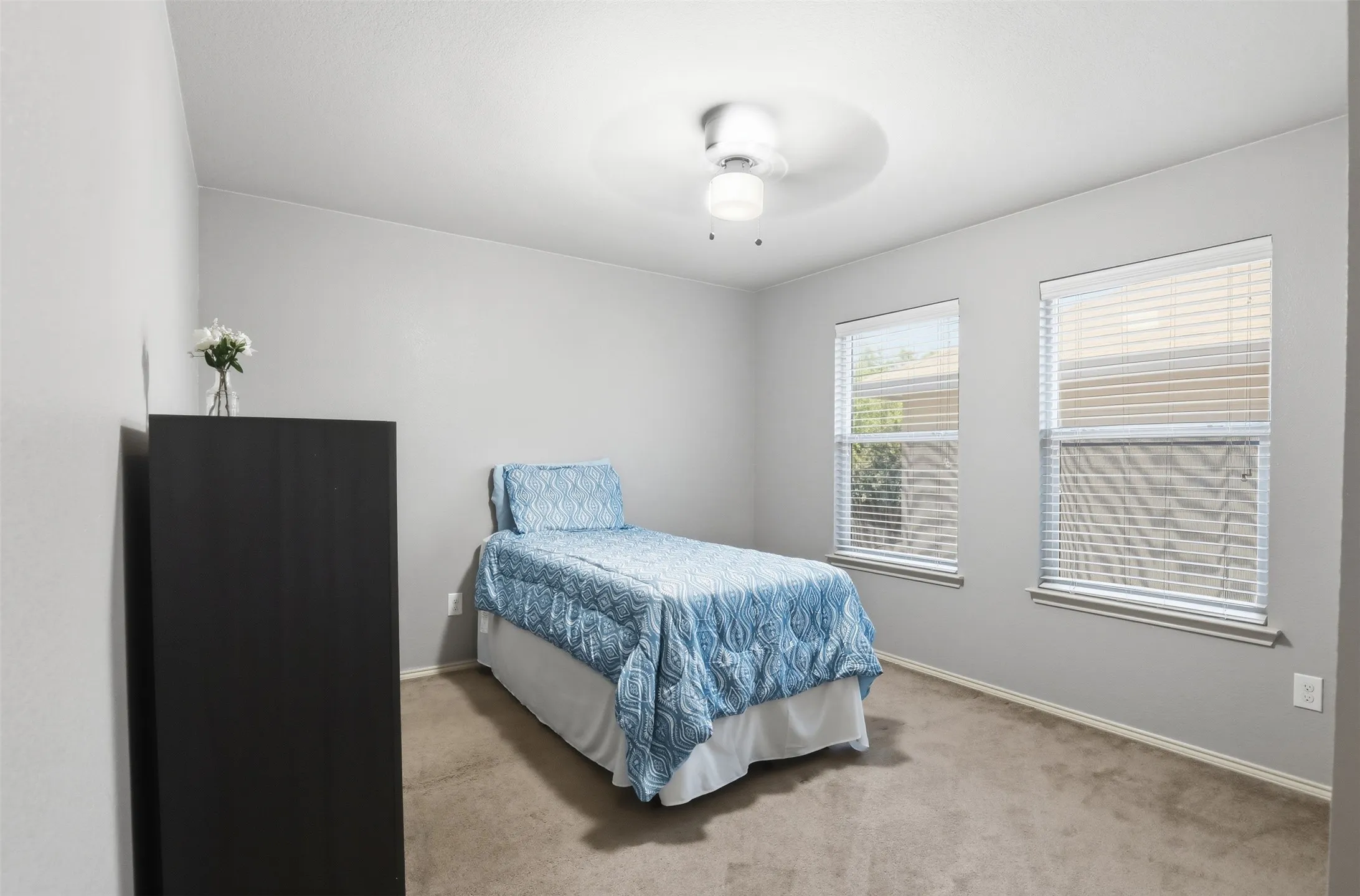 Bedroom featuring neutral wall paint, two windows with blinds, a ceiling fan with integrated lighting