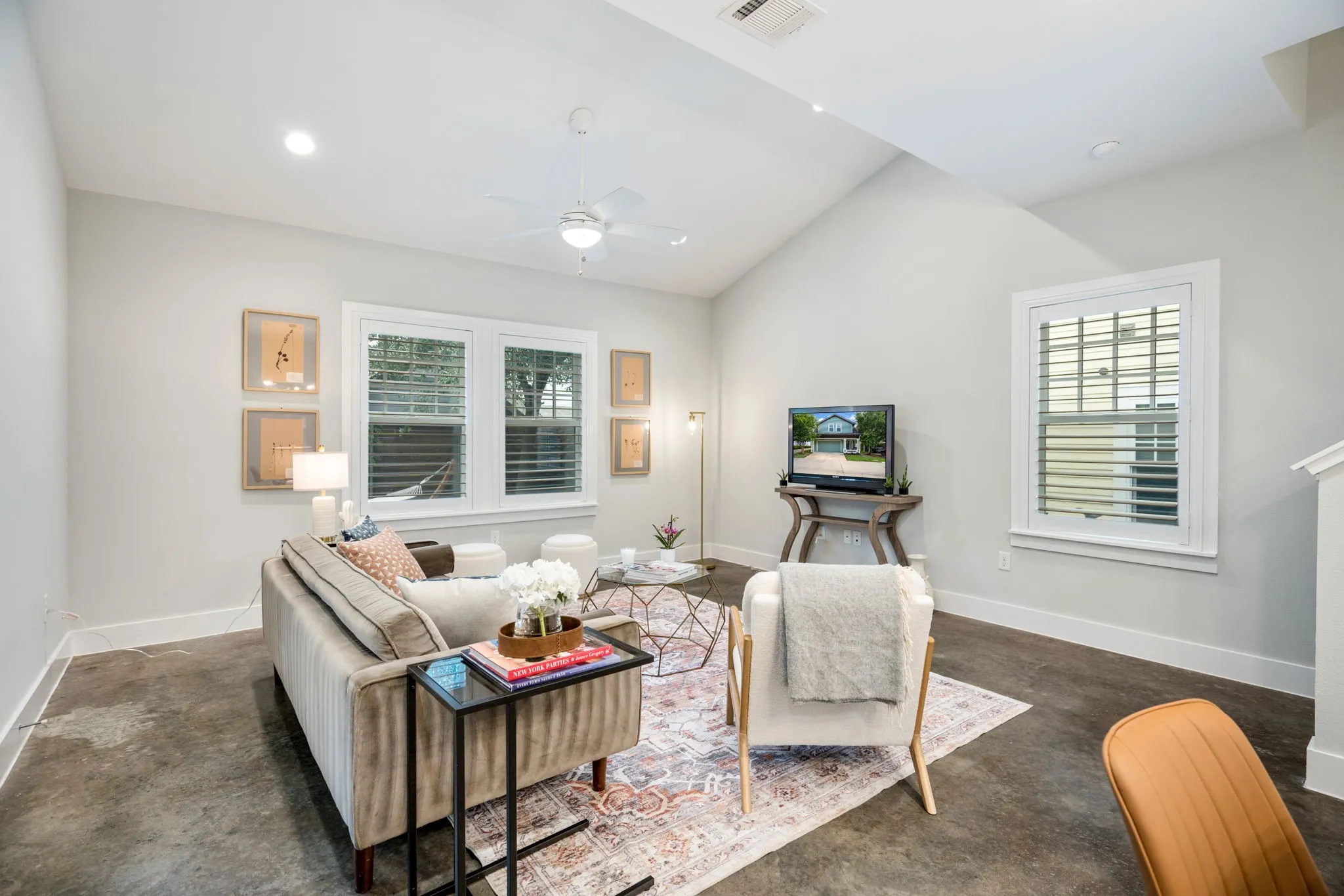     Light-filled living room with soaring ceilings, polished concrete floors, and backyard access.