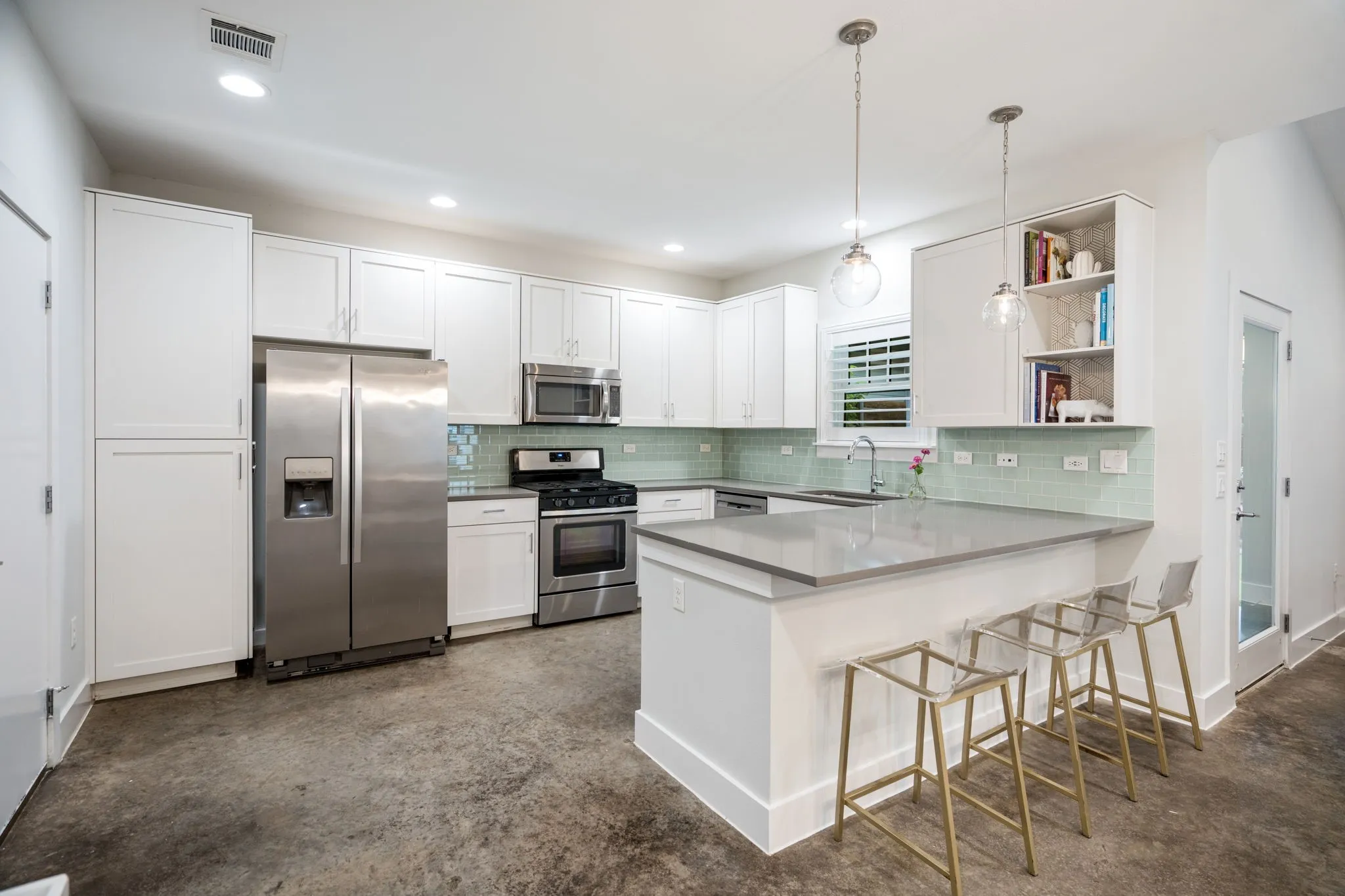     Bright and functional kitchen featuring quartz countertops and designer tile backsplash.