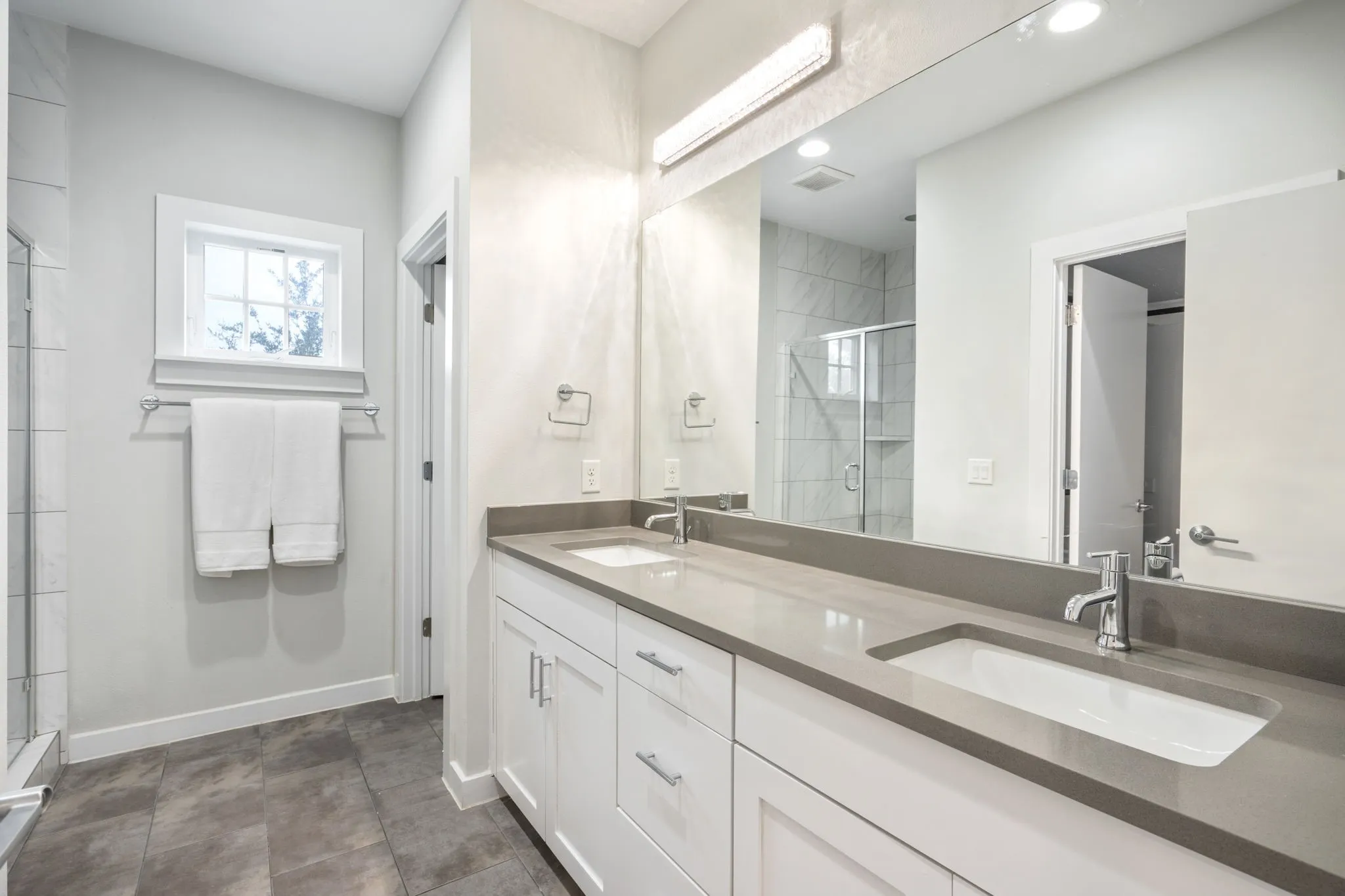     Spacious primary bath featuring dual vanities, modern finishes, and an oversized mirror.