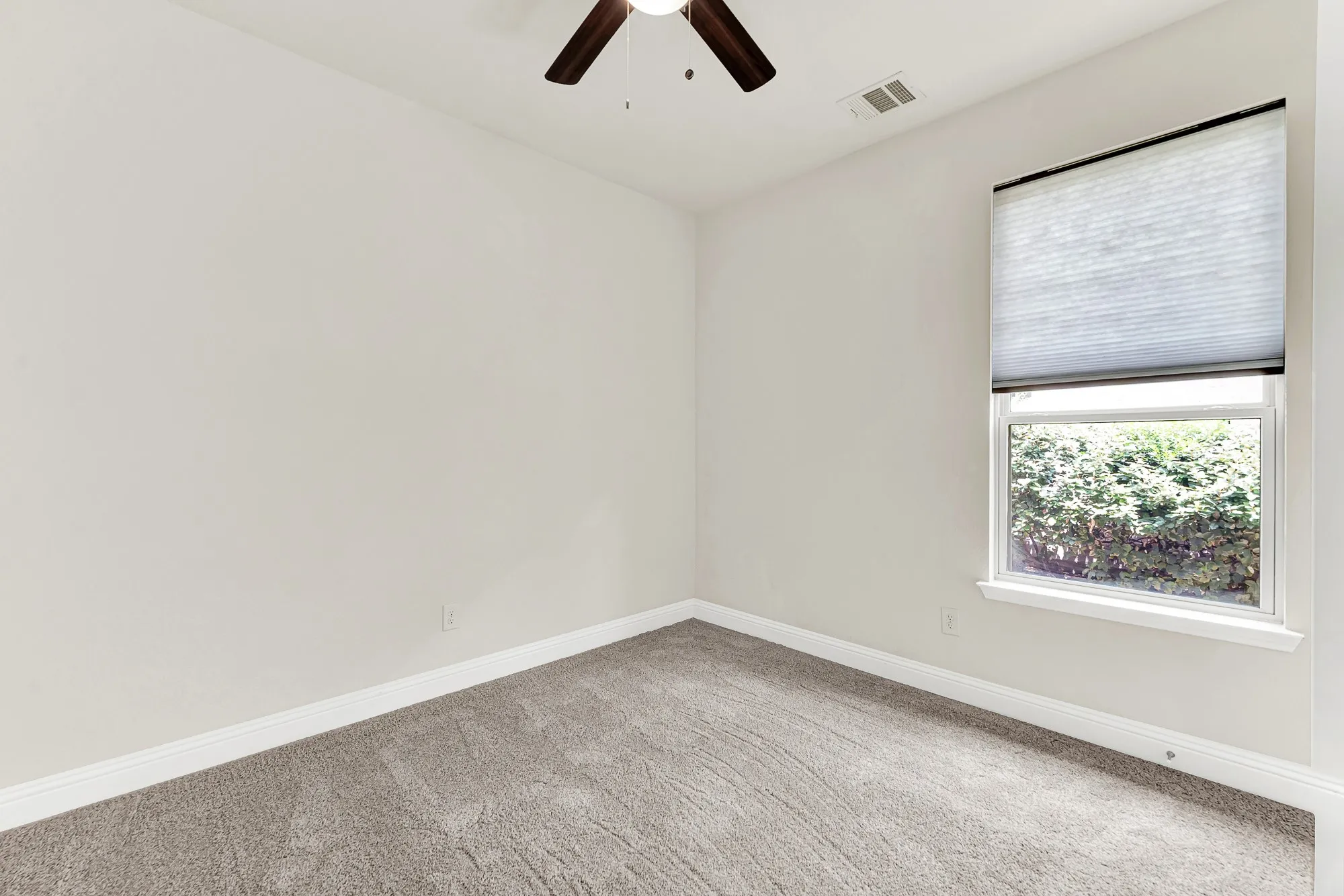 A wide window pulls a refreshing view of the outdoor greenery directly into this serene bedroom space. Your overnight guests will appreciate waking up to peaceful morning light, feeling entirely welcome and comfortably at home.