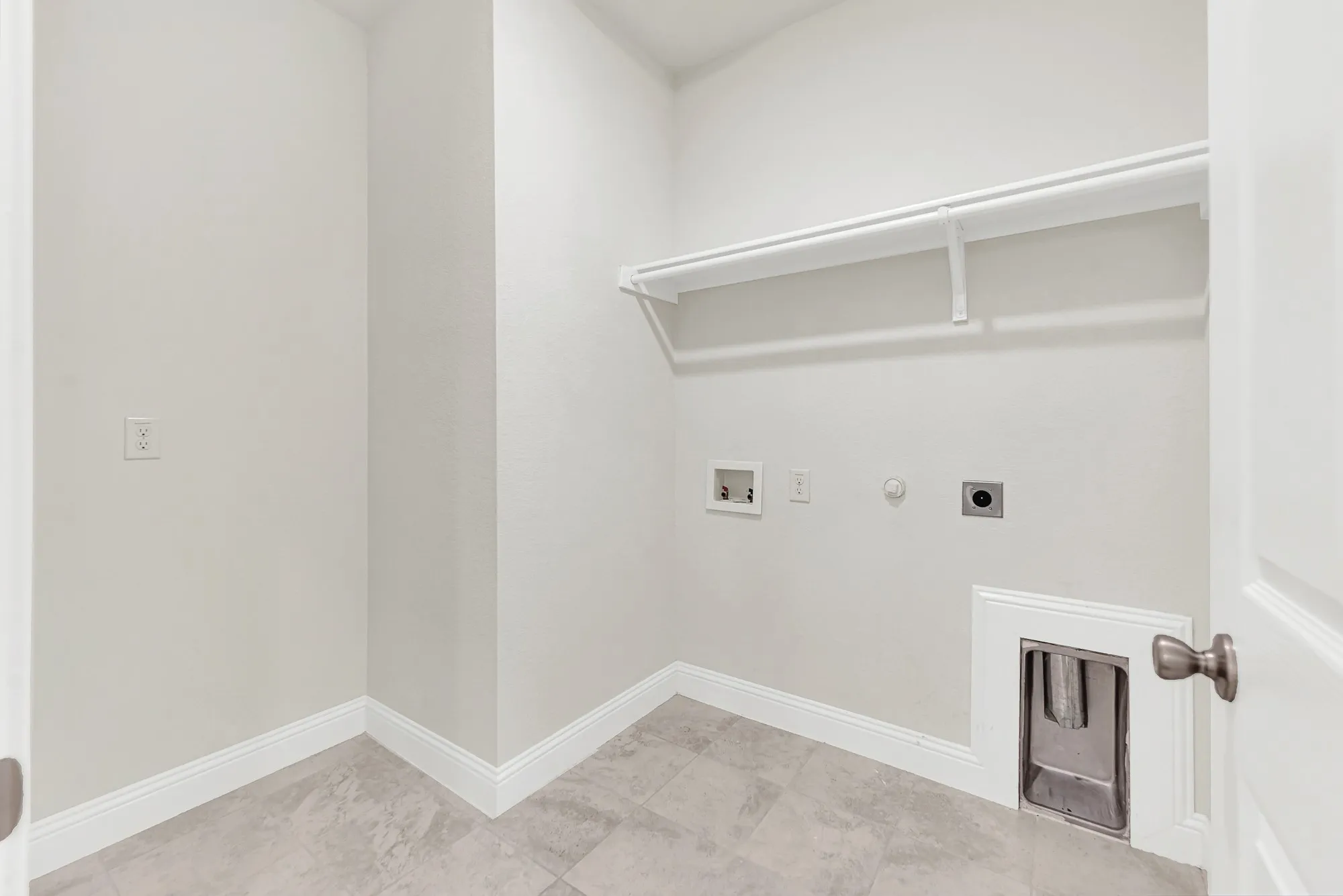 Smart, built-in shelving maximizes vertical square footage, creating an exceptionally organized backdrop over the durable tiled floor. This practical setup simplifies your weekly laundry routine, keeping everything beautifully in its place.
