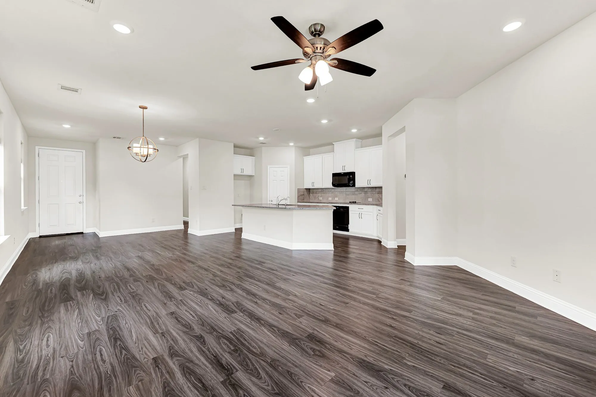 The sweeping, continuous grain of dark luxury flooring expands the room visually, pulling light from the kitchen into the heart of the home. It sets a dramatic backdrop for a vibrant housewarming party where guests mingle effortlessly between spaces.