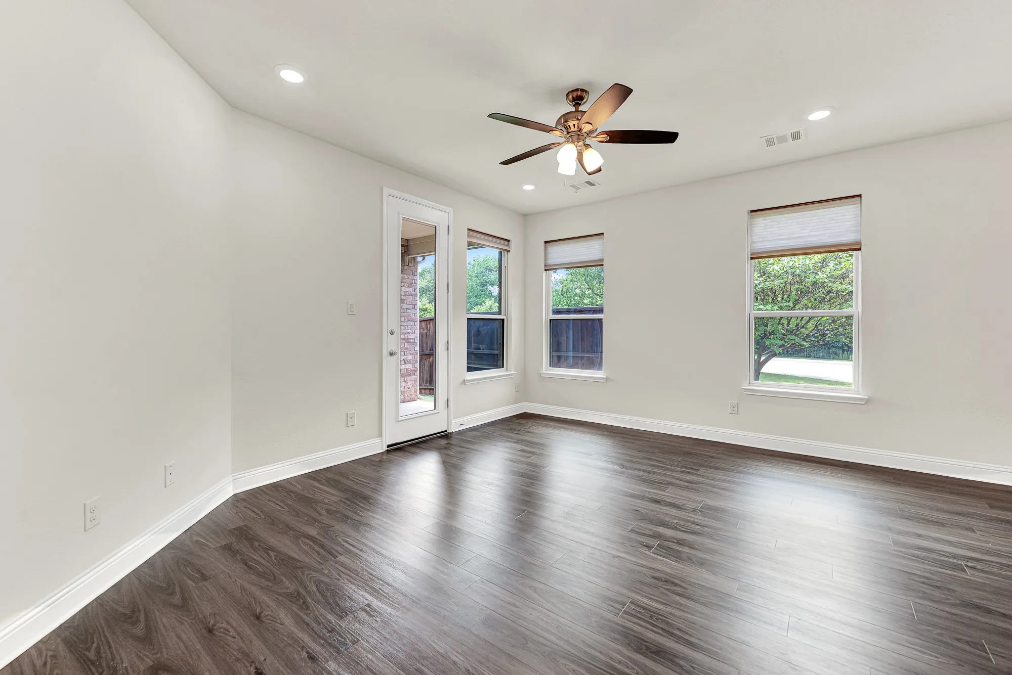 Multiple viewports wrap the corner of the room, framing leafy green treetops like living pieces of art against crisp neutral walls. Imagine starting a slow weekend morning right here, watching the neighborhood come alive while the sun climbs higher in the sky