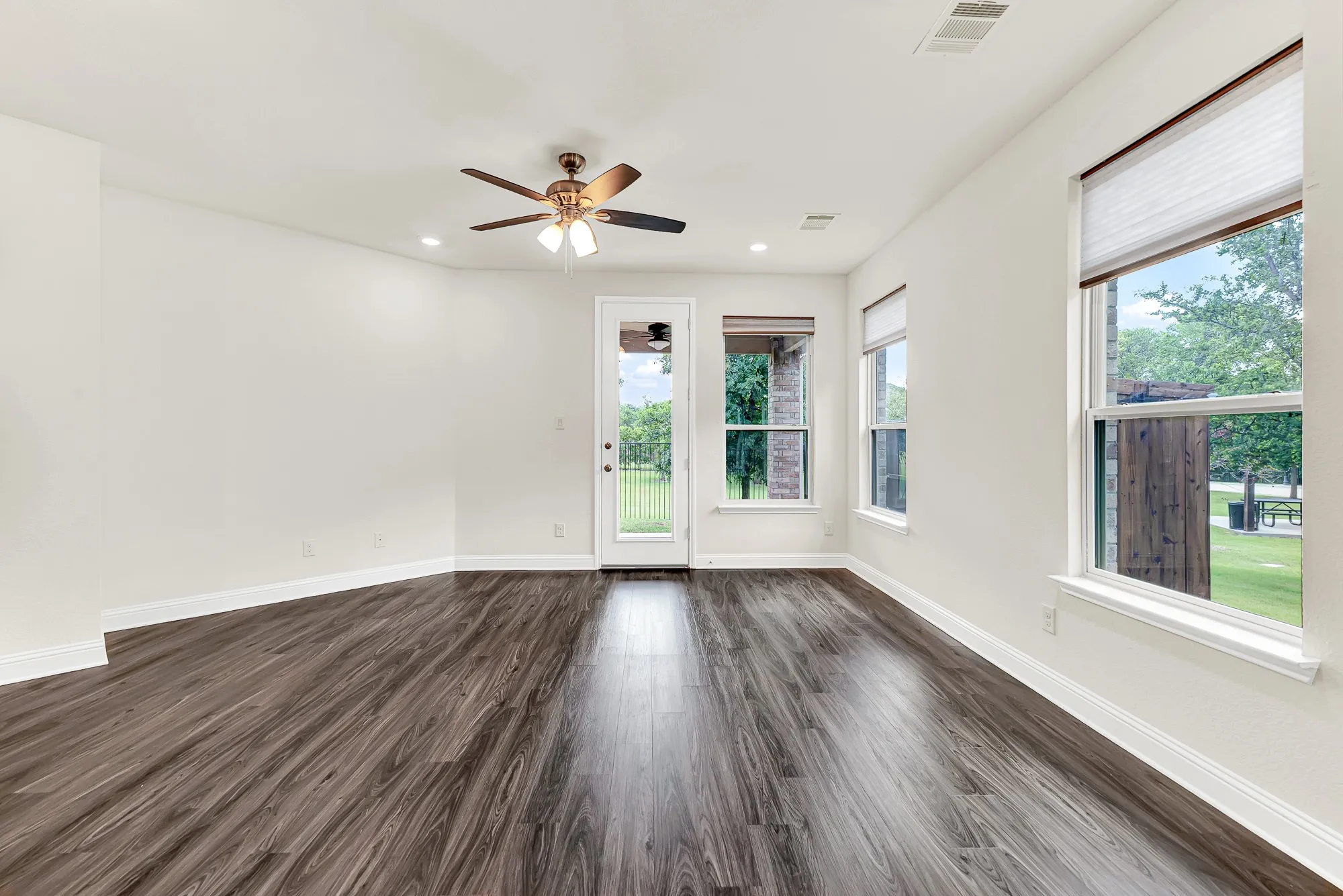 The back glass door floods the dark plank flooring with a beautiful stream of natural daylight. It is a welcoming space to unwind during a quiet evening retreat, watching the leaves rustle in the park just beyond your windows.