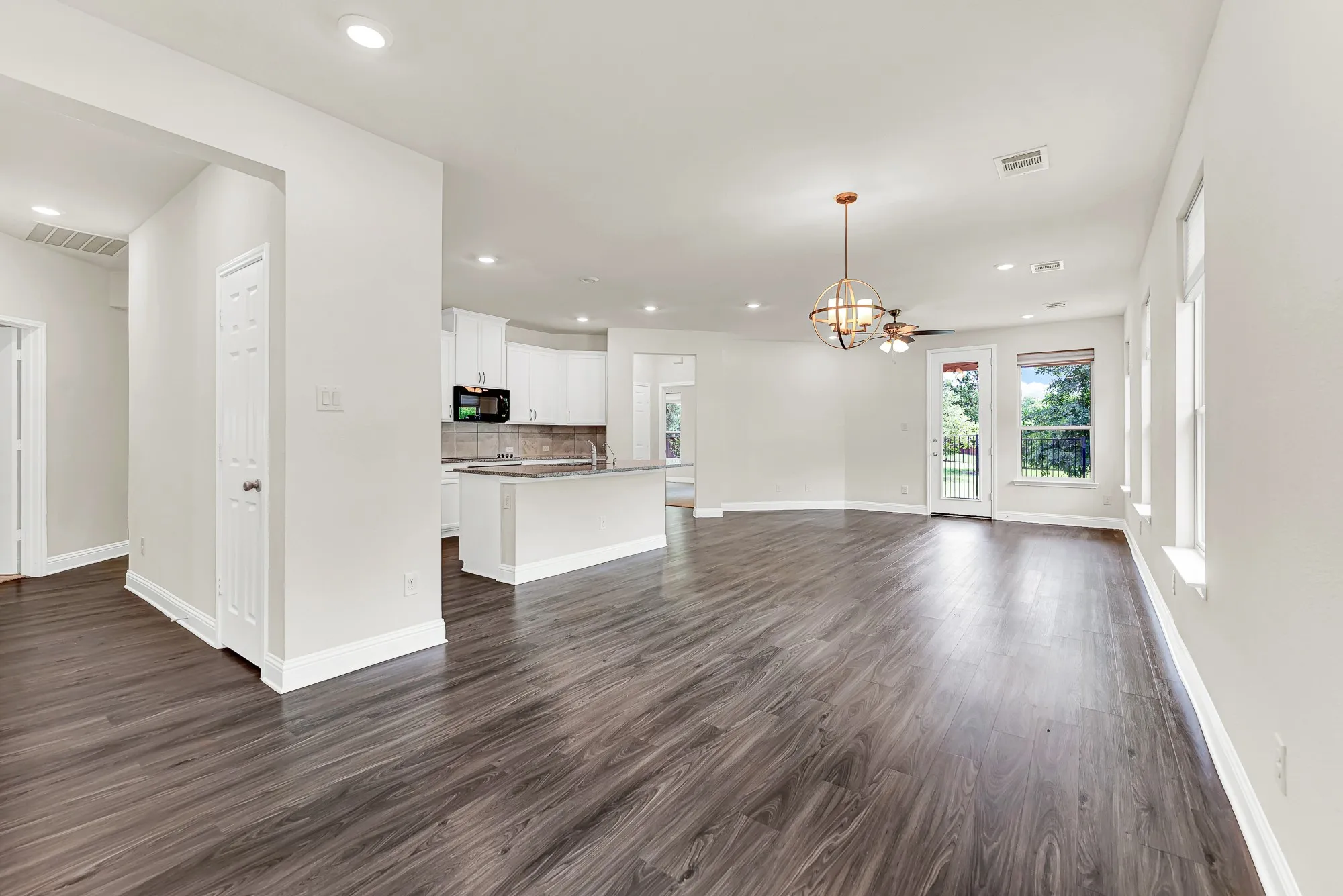 A geometric orb chandelier grounds the dining zone, establishing a distinct architectural point of view within the seamless, flowing layout. It is the ultimate setting for an intimate, candlelit dinner party that casually transitions over to the kitchen island.