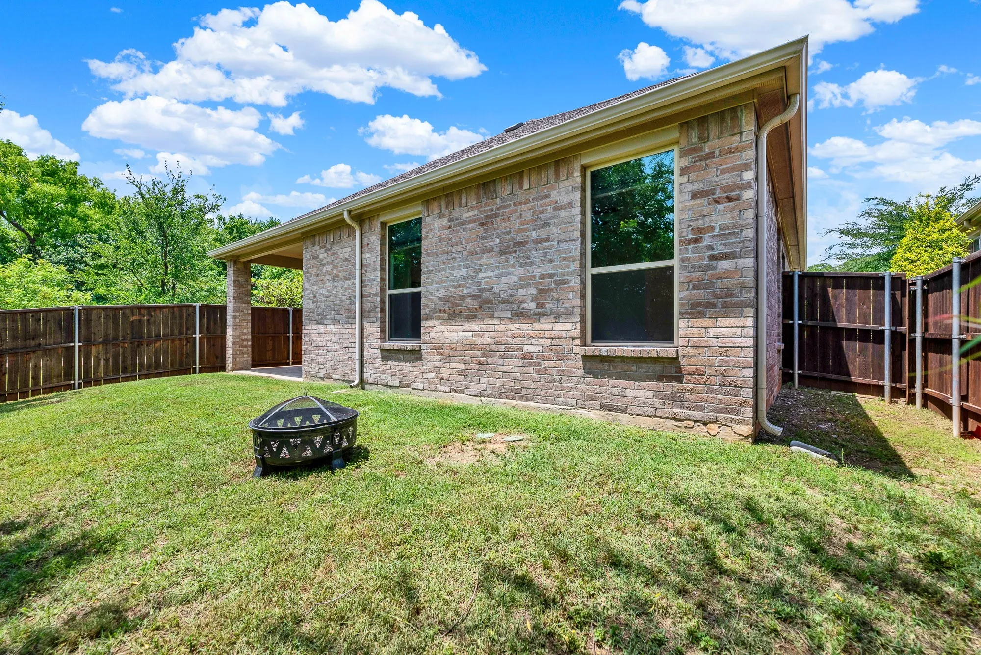 Large, strategically placed windows punctuate the classic brick facade, reflecting the brilliant blue sky and tracking the afternoon sun. Picture yourself looking out, keeping a watchful eye on loved ones playing in the secure yard.