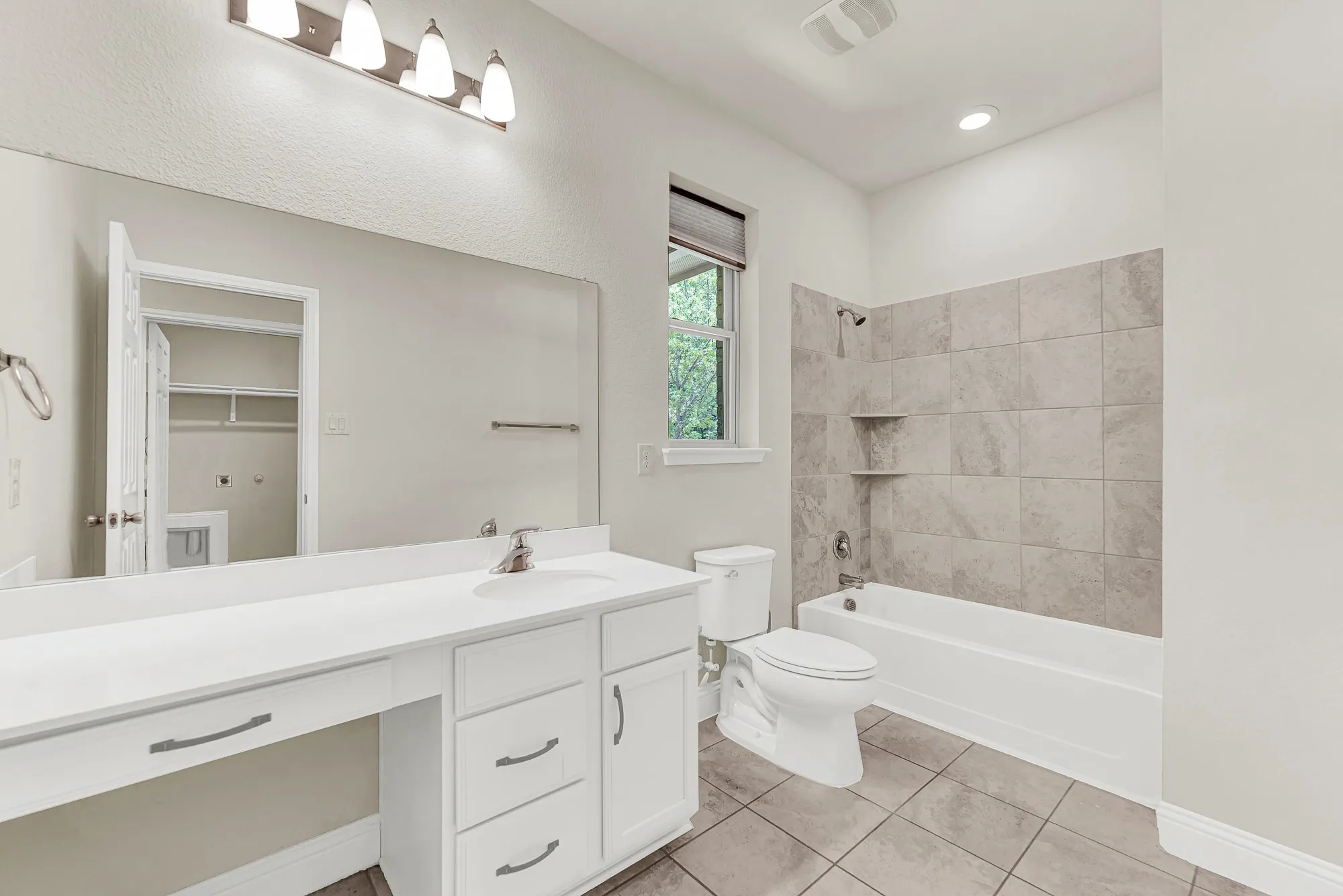The pristine shower-tub combination reflects the bright overhead lighting, emphasizing a meticulously clean and structured layout. It offers a fresh, private spot to wash away the day during a relaxing evening routine.