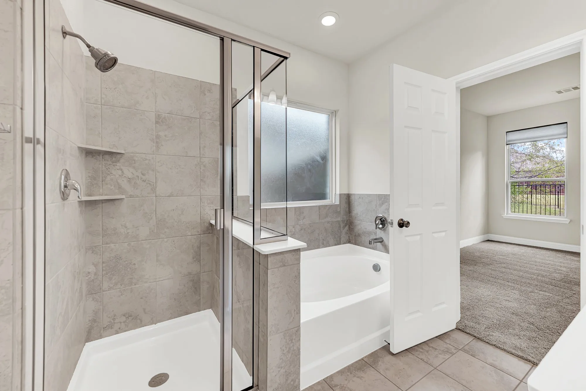 The glass-enclosed shower integrates seamlessly with the deep-toned tile work, balancing structure with functional design. Treat yourself to a long, restorative soak in the adjacent tub, letting the quiet warmth wash away the day.