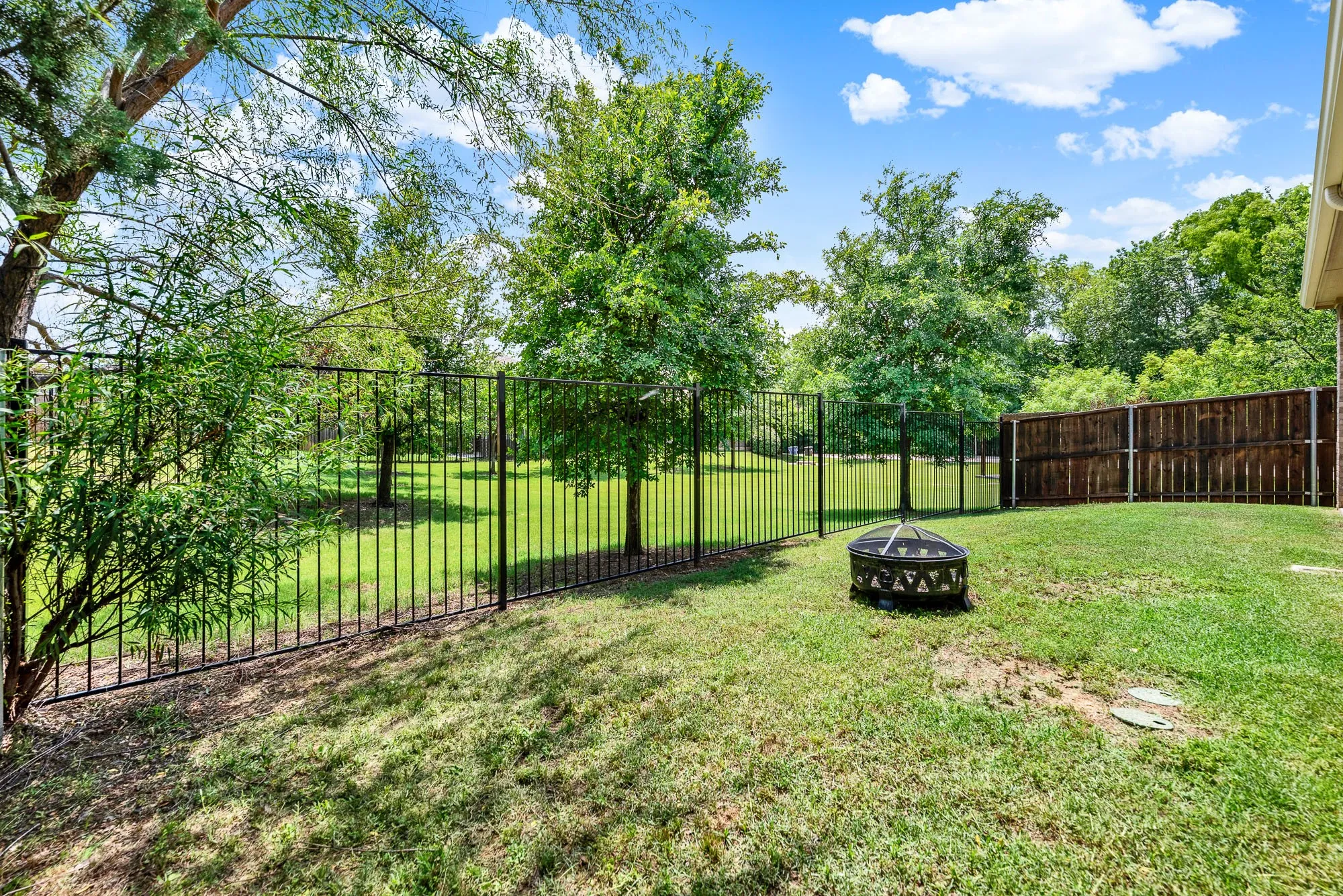The sleek wrought-iron fencing offers an unobstructed view of the serene green landscape, letting natural sunlight flood the entire lawn. It is the perfect spot to gather around a crackling fire pit on a crisp autumn evening, sharing stories beneath a canopy of stars