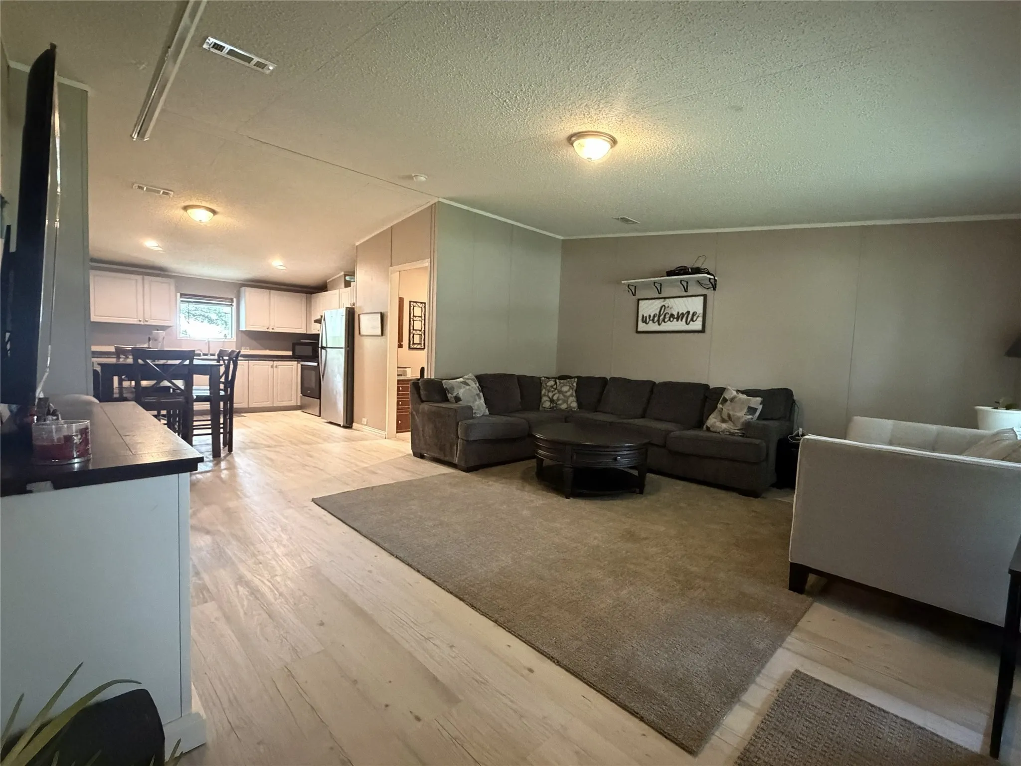 Open-concept living space featuring wood-finish flooring, recessed lighting, and a neutral color palette