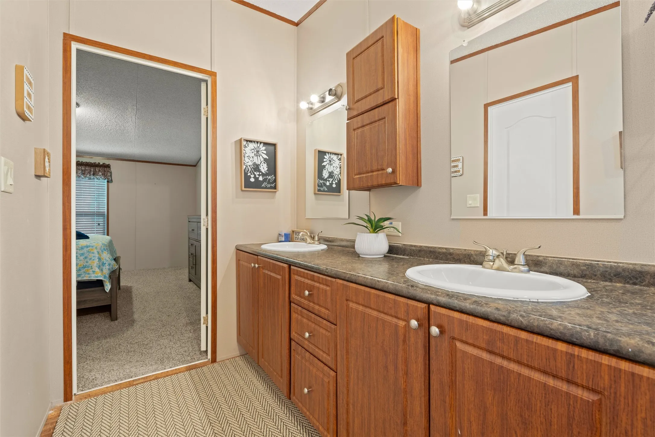 Bathroom featuring a double vanity with wood-finish cabinetry, integrated sinks, a laminate countertop, and individual mirrors with overhead lighting