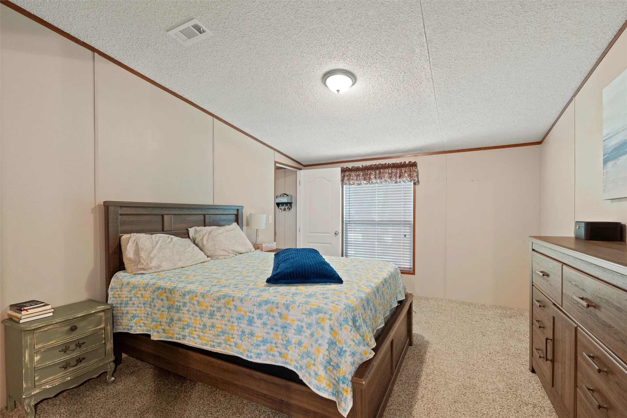 Carpeted room featuring a ceiling-mounted light fixture, panel walls with wood trim, and a window with horizontal blinds