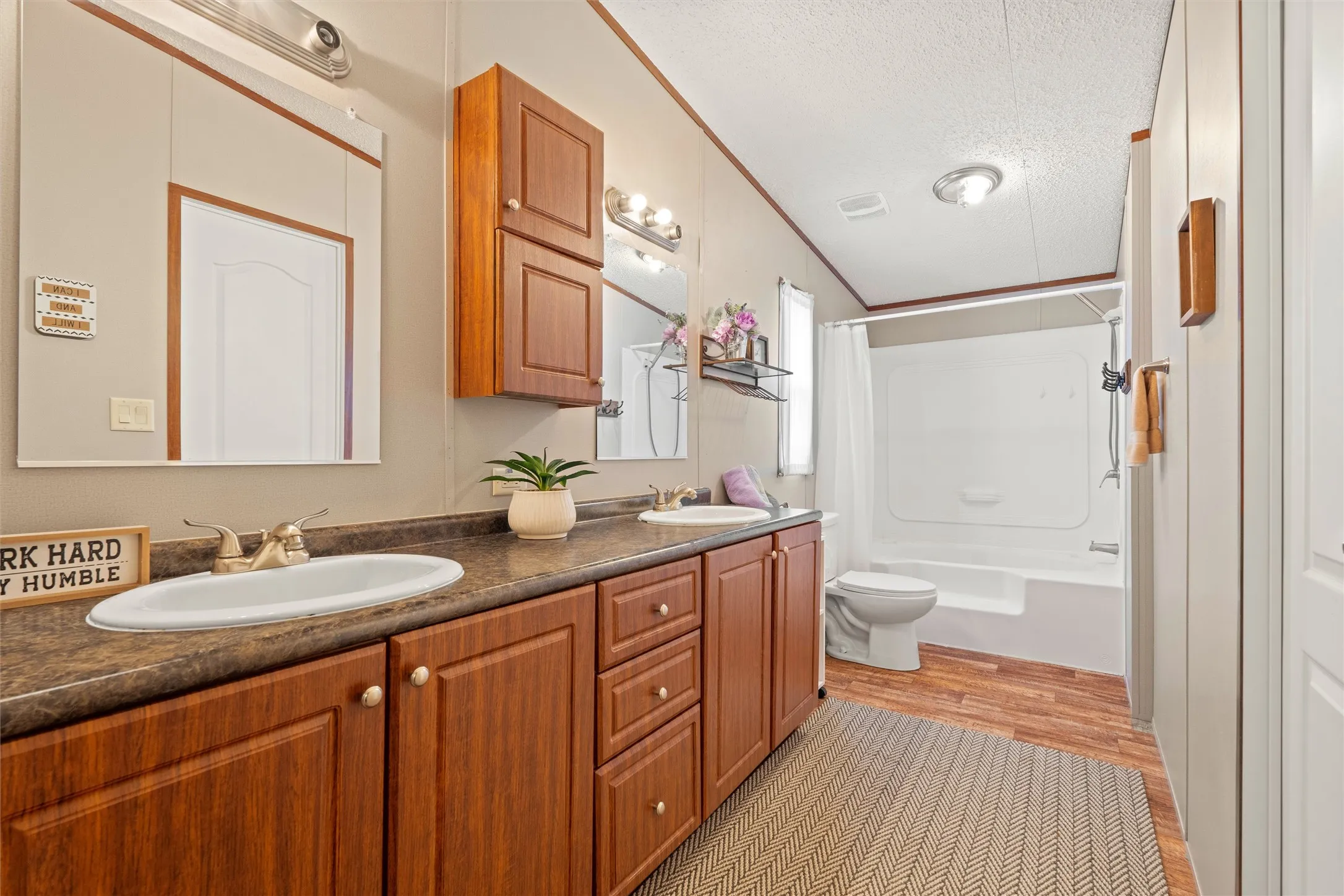 Double vanity featuring wood-finish cabinetry and ample countertop space