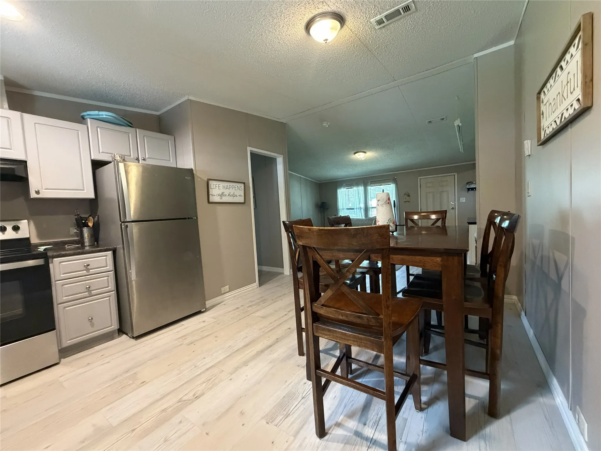 Kitchen area featuring light wood-finish flooring, white cabinetry, and stainless steel appliances