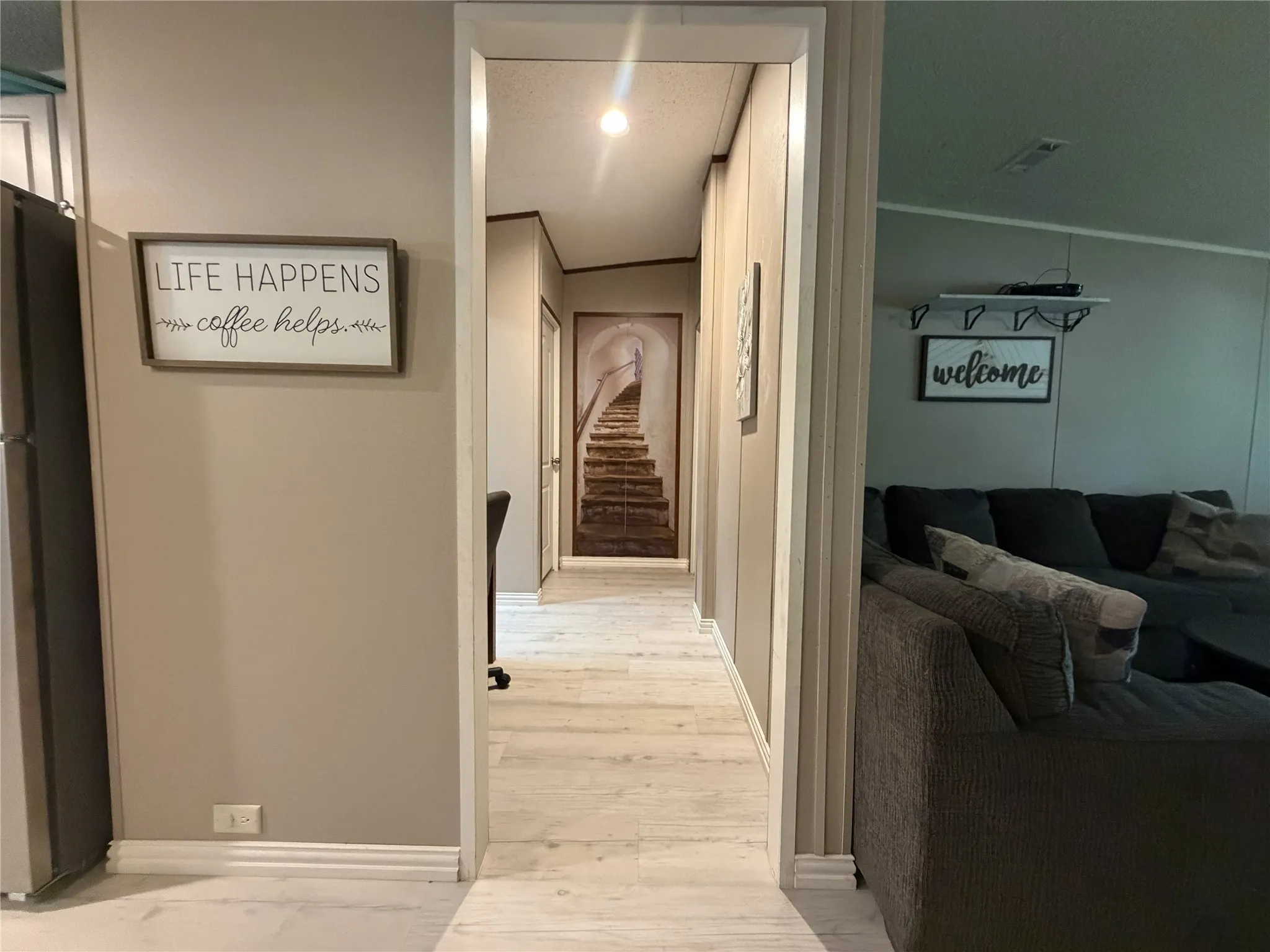Central hallway featuring light-toned wood-finish flooring, white trim, and a recessed light fixture