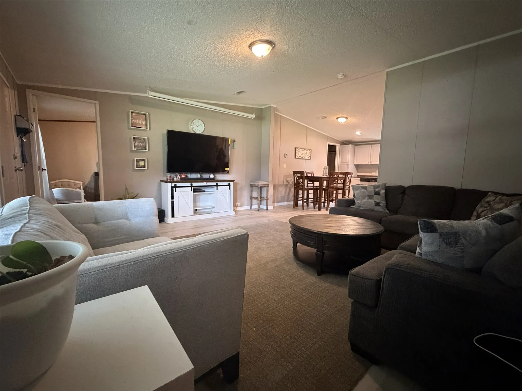 Open-concept living space featuring mixed flooring, a dedicated dining area, and a partial view of the kitchen