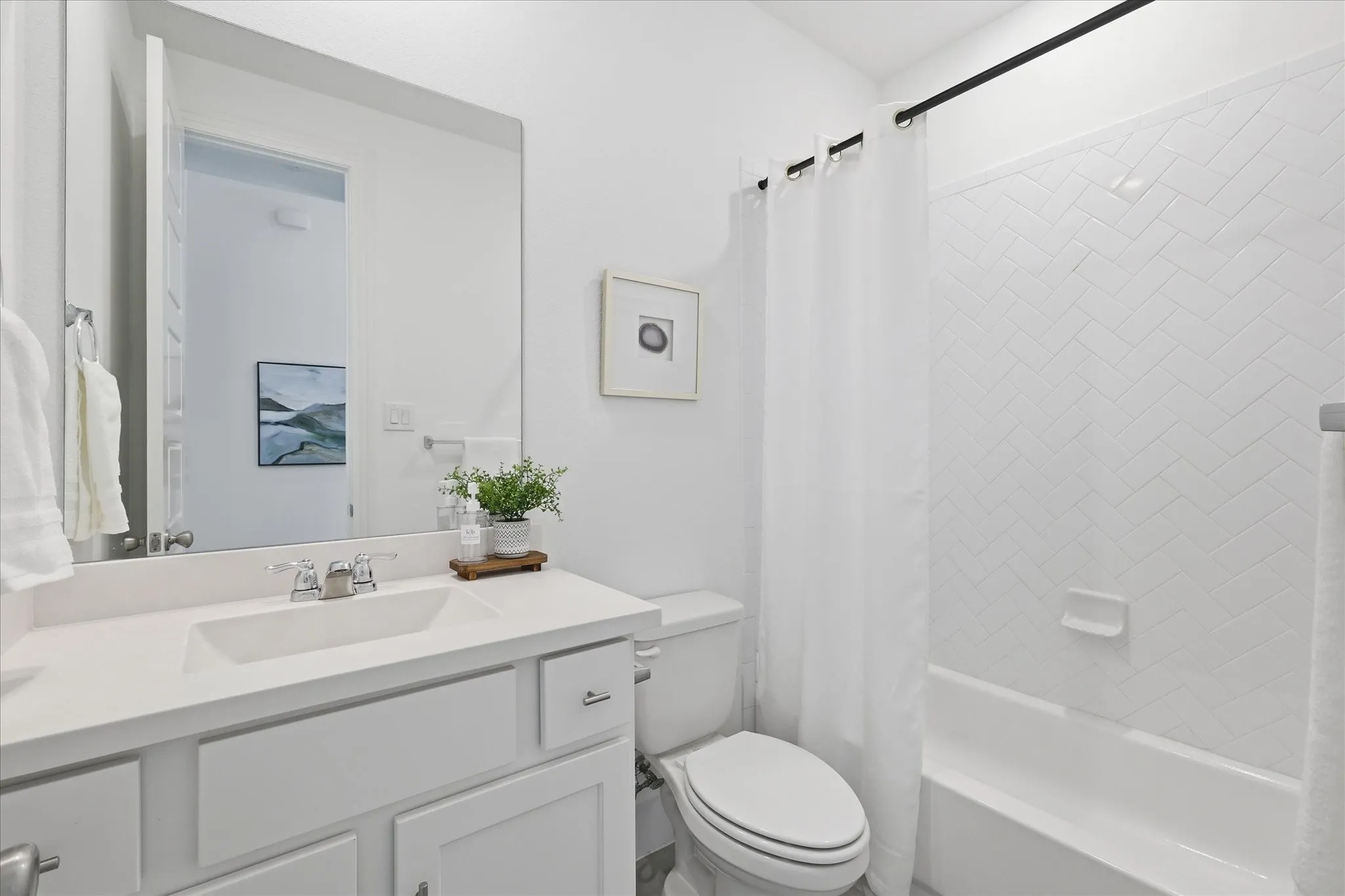 Bathroom featuring a white vanity with integrated sink, chrome faucet, and a large wall-mounted mirror