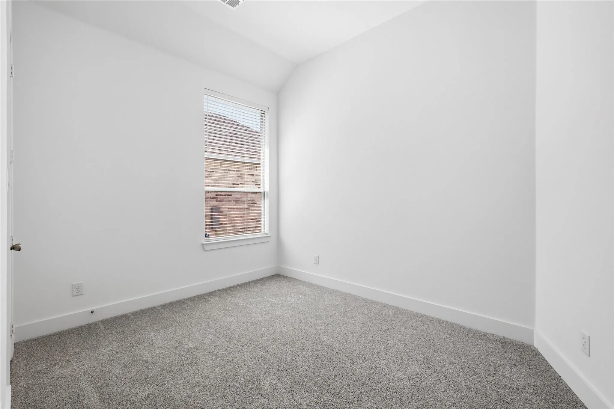 Carpeted room featuring a single window with blinds, white walls, and bright baseboards