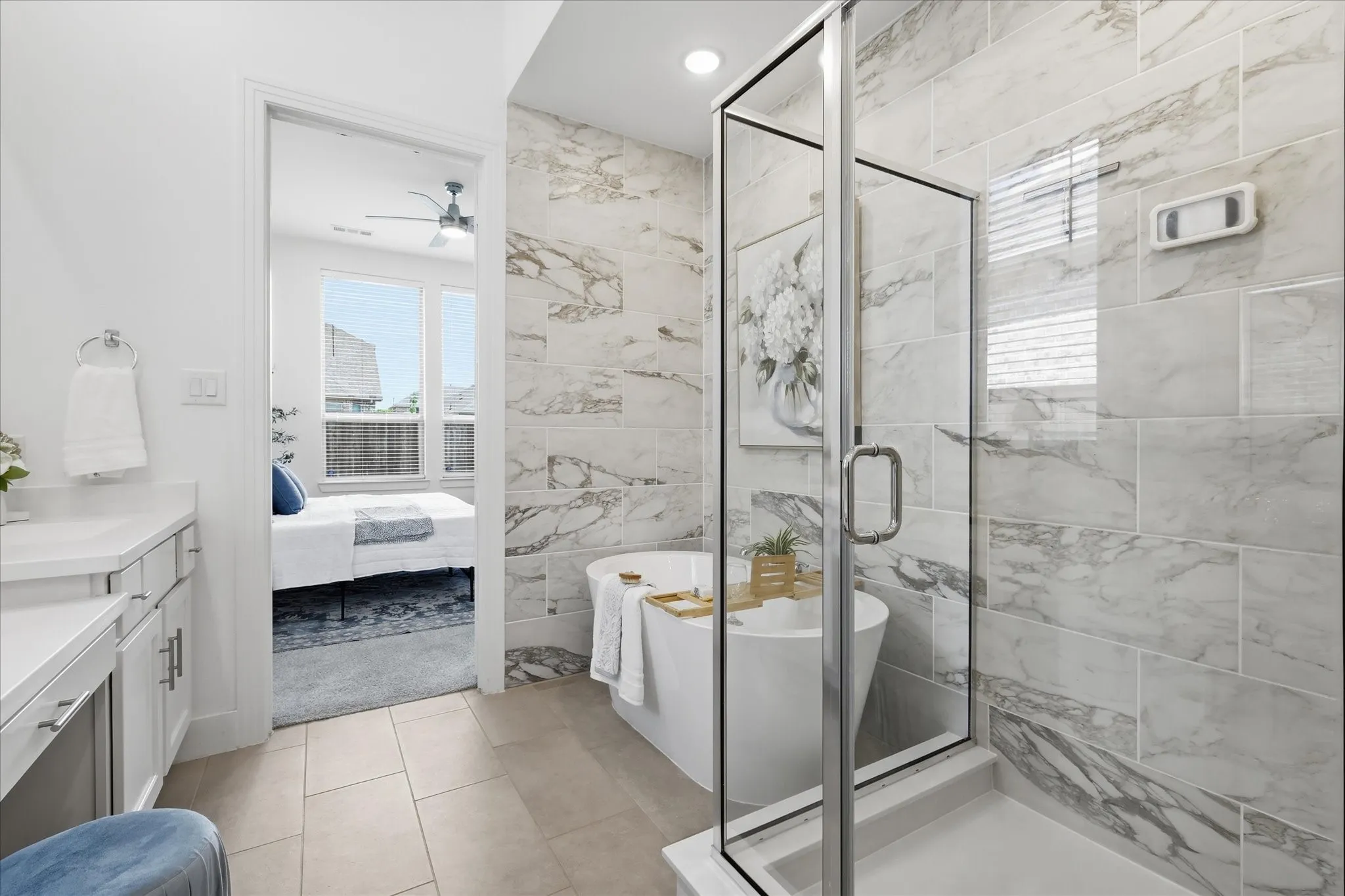 Bathroom featuring a freestanding tub, glass-enclosed shower, and vanity with a light-toned countertop