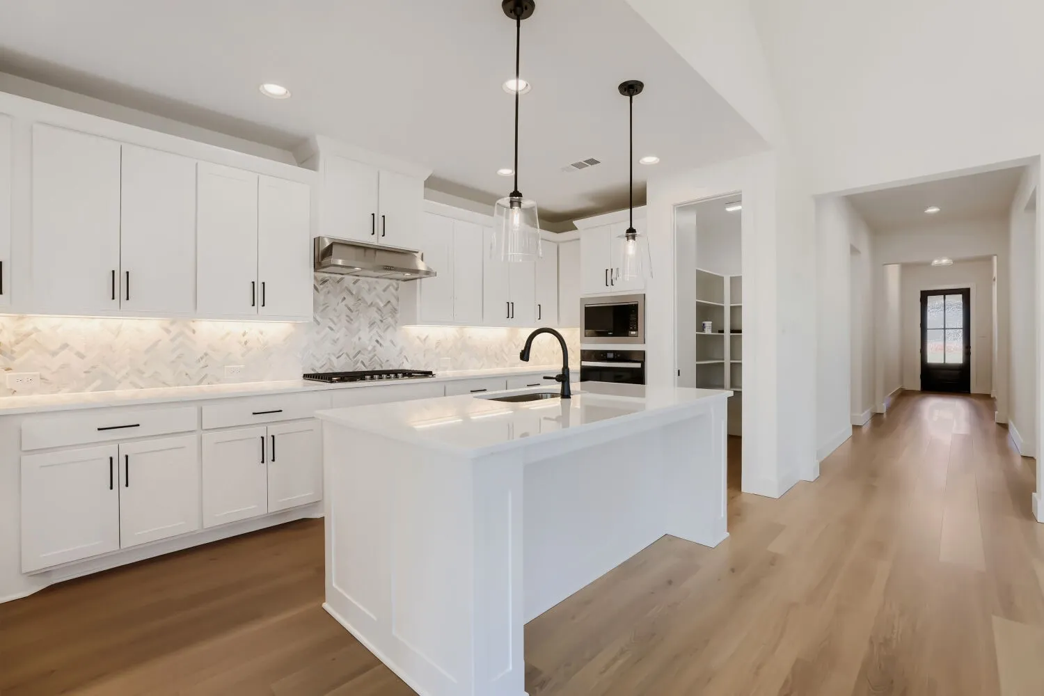 Kitchen featuring white cabinetry, a large center island, herringbone tile backsplash, and recessed lighting