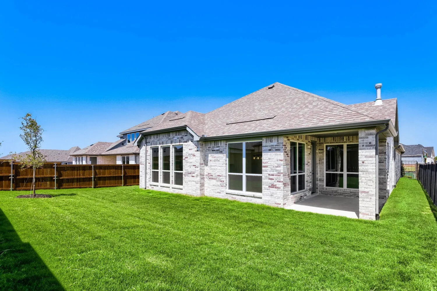 Expansive backyard featuring a manicured lawn, a covered patio, and a privacy fence